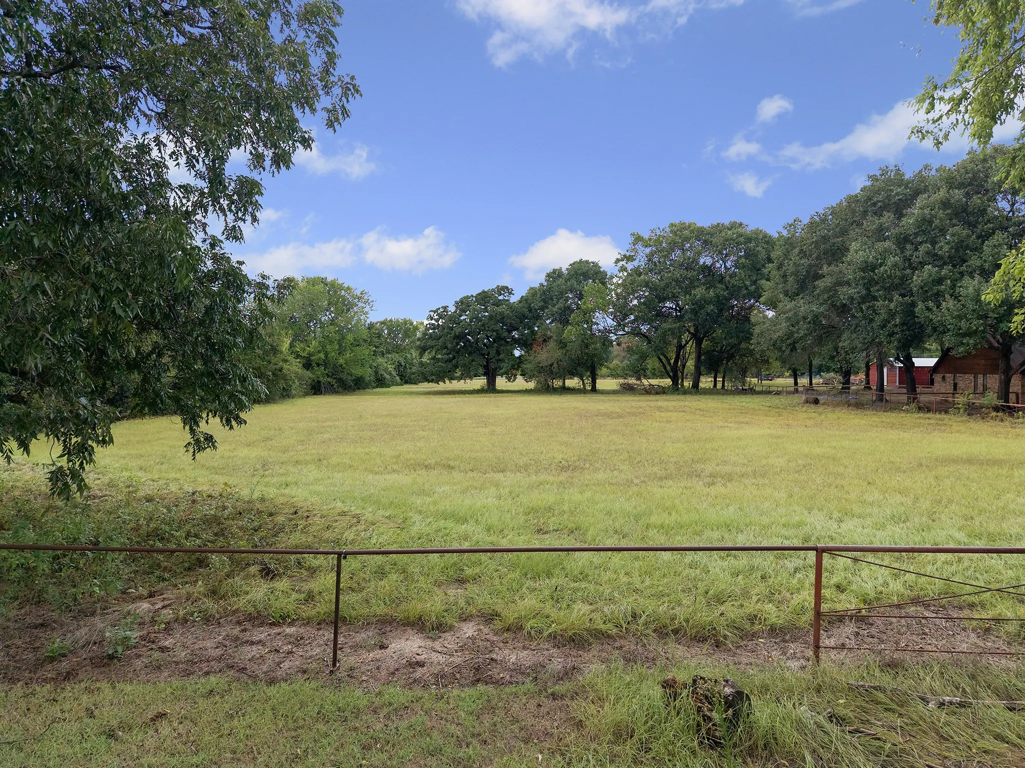Expansive green field surrounded by mature trees