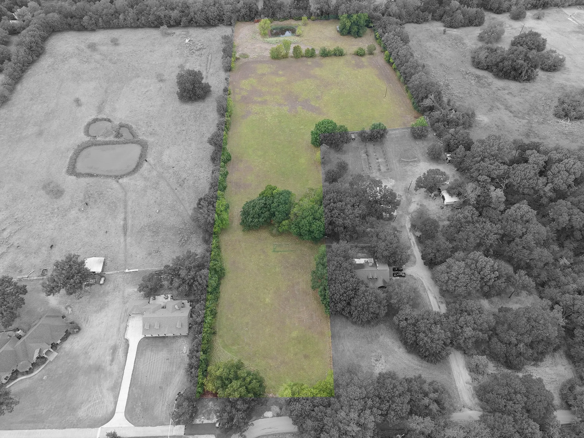 Expansive land parcel featuring open fields, natural tree lines, and a visible pond