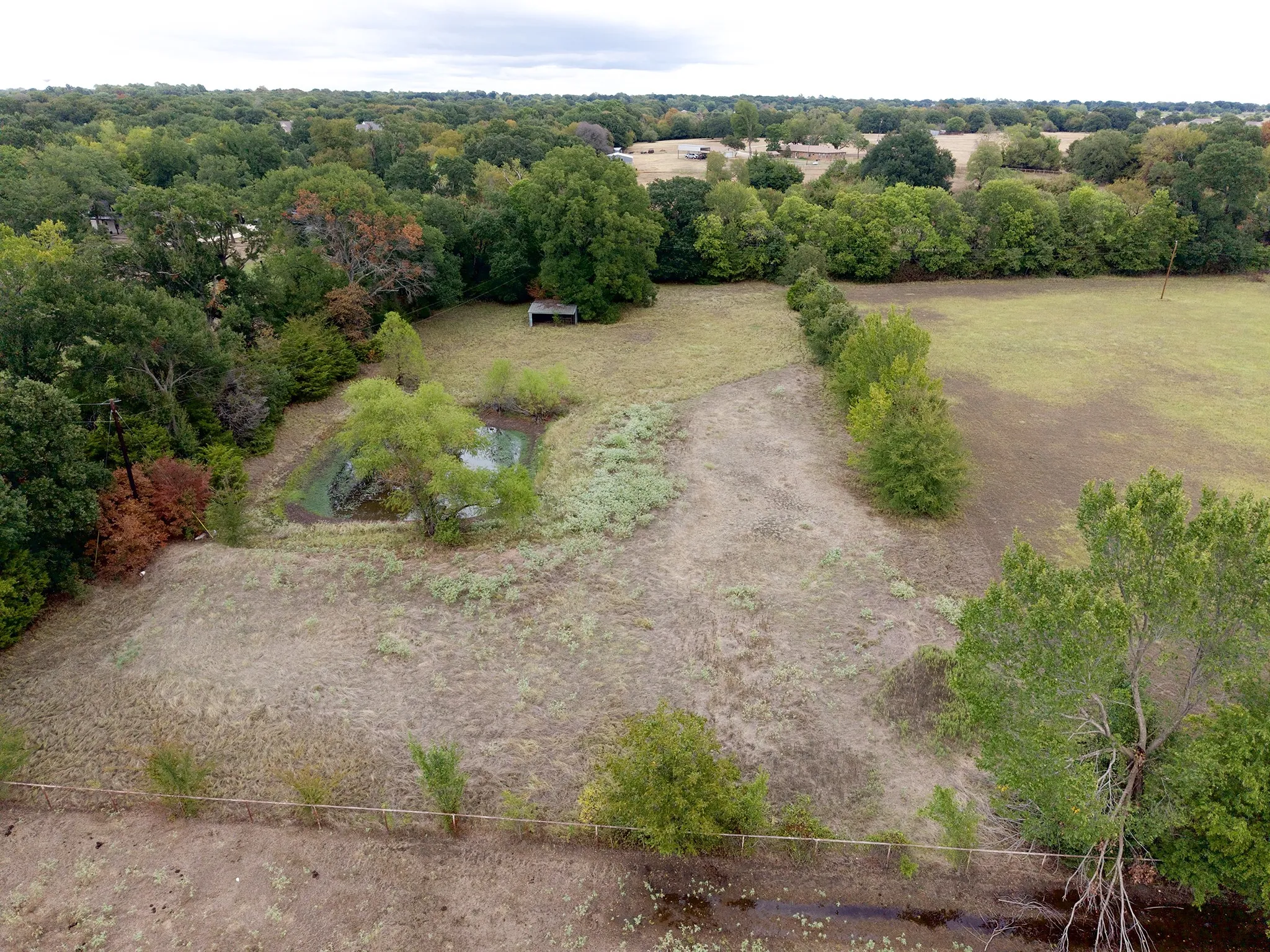Expansive property featuring a pond, established trees, and natural landscaping