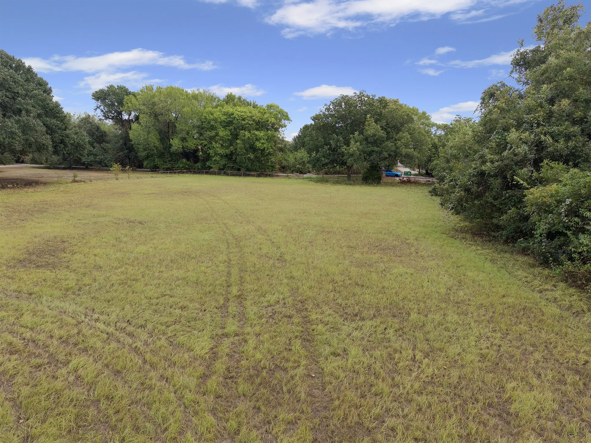 Expansive grassy area with mature trees bordering the perimeter