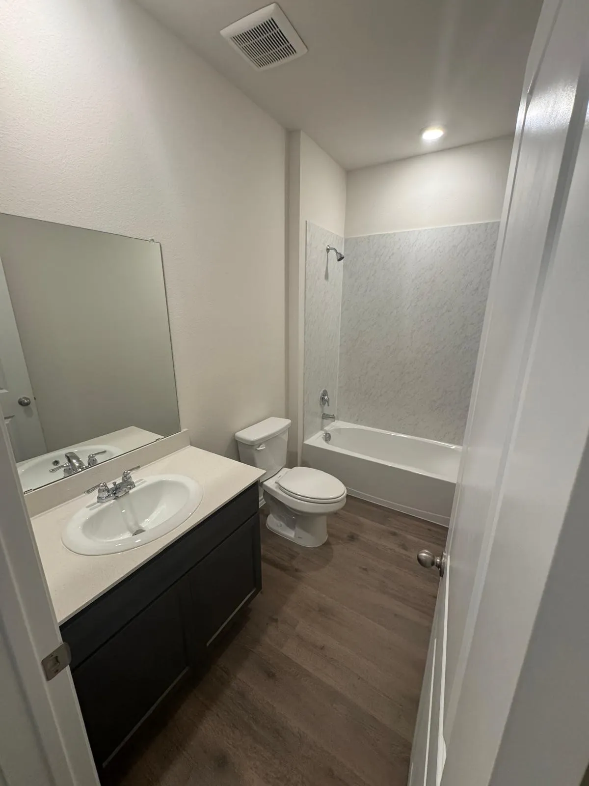 Bathroom with dark wood-style flooring, shower / bath combination, and vanity