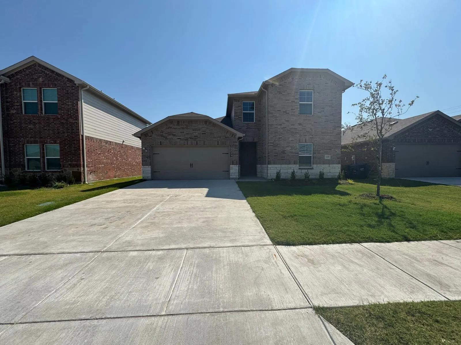 Traditional-style house with brick siding, concrete driveway, a front lawn, and an attached garage