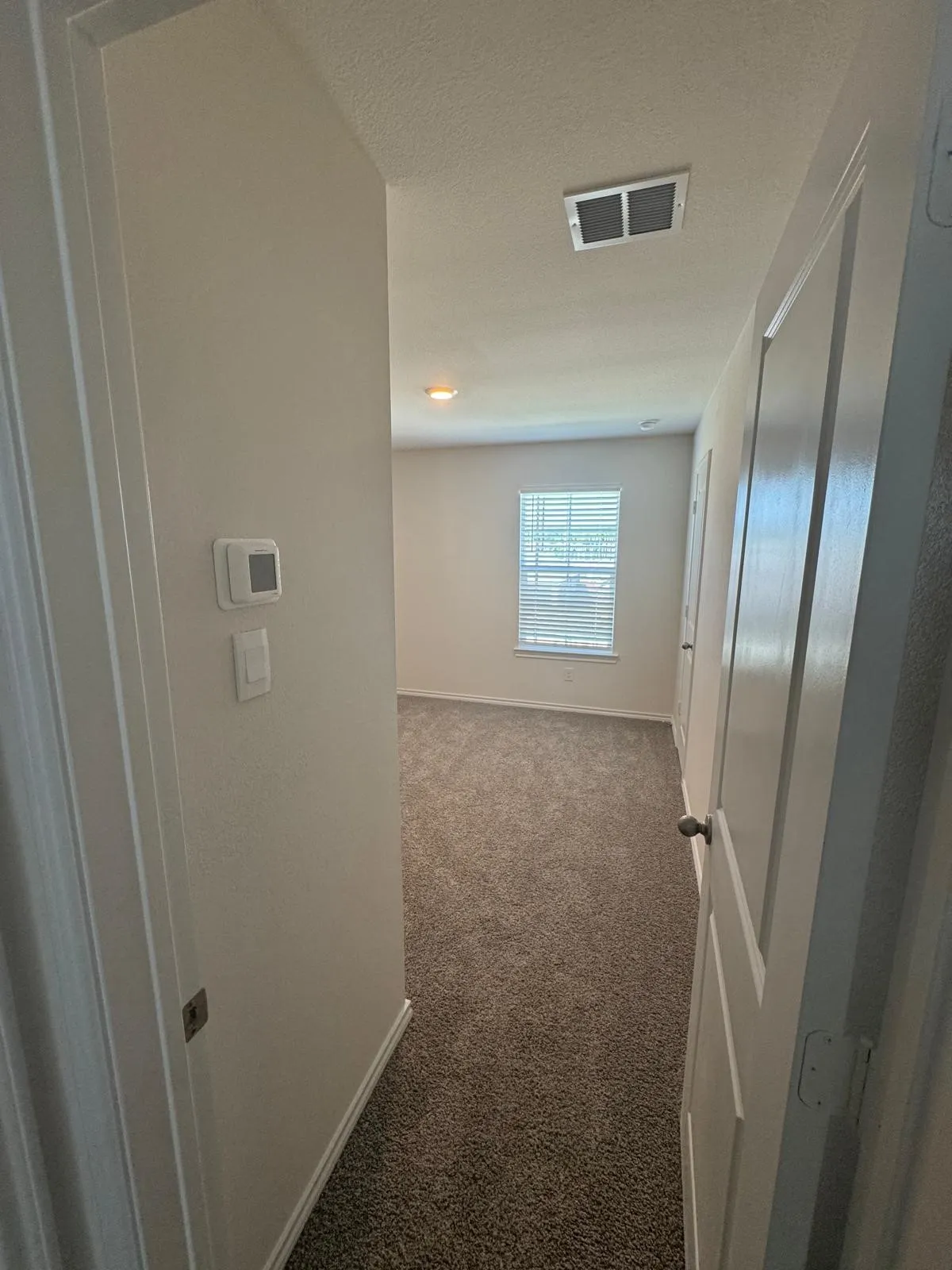 Hall featuring dark colored carpet and a textured ceiling