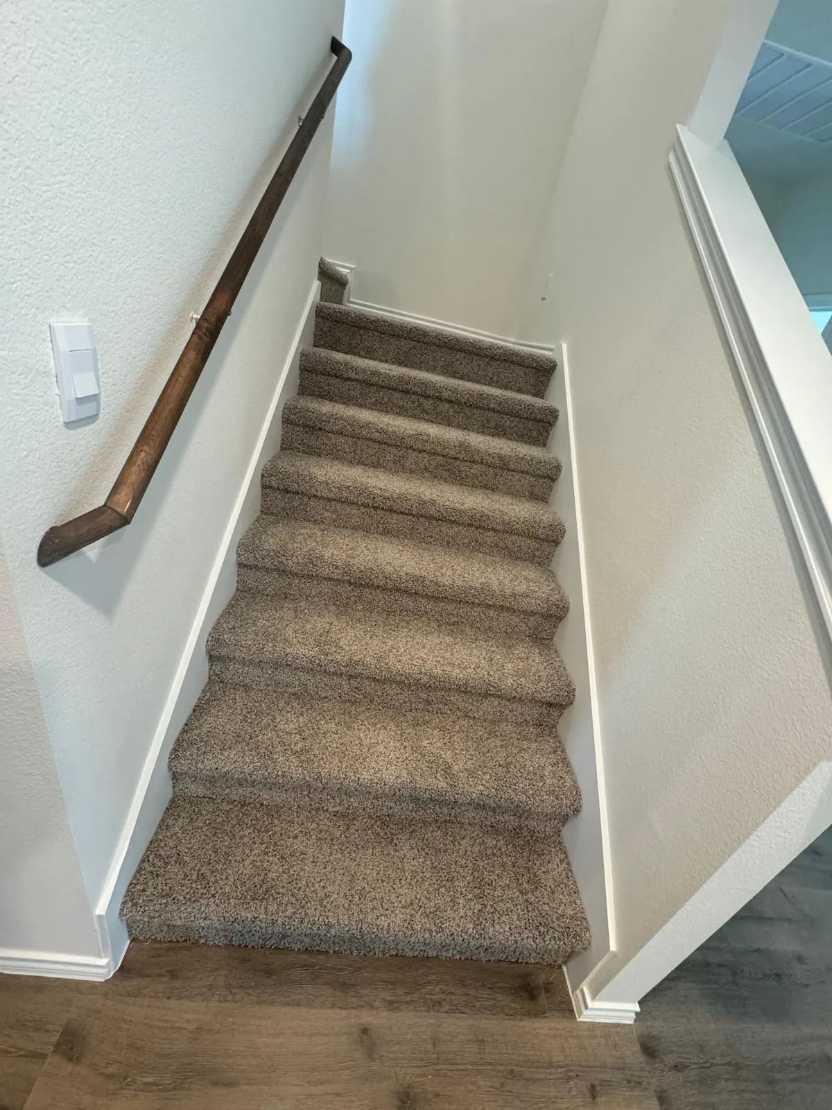 Staircase featuring a textured wall and wood finished floors