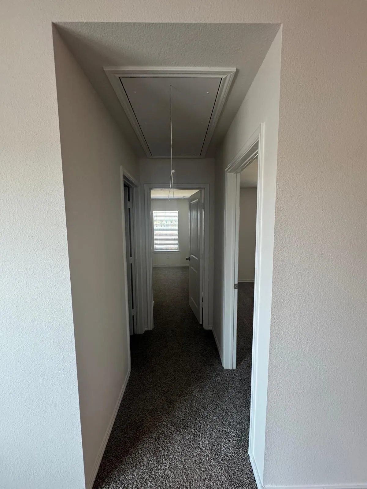 Corridor featuring attic access, cooling unit, and dark carpet