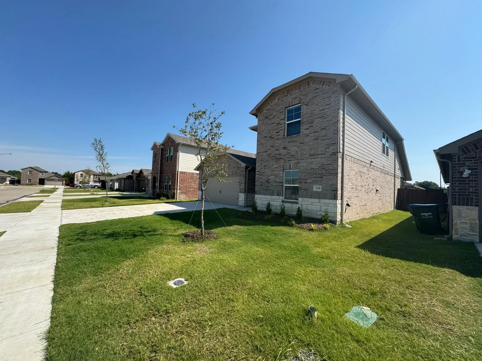 View of side of home featuring brick siding, concrete driveway, a lawn, and an attached garage
