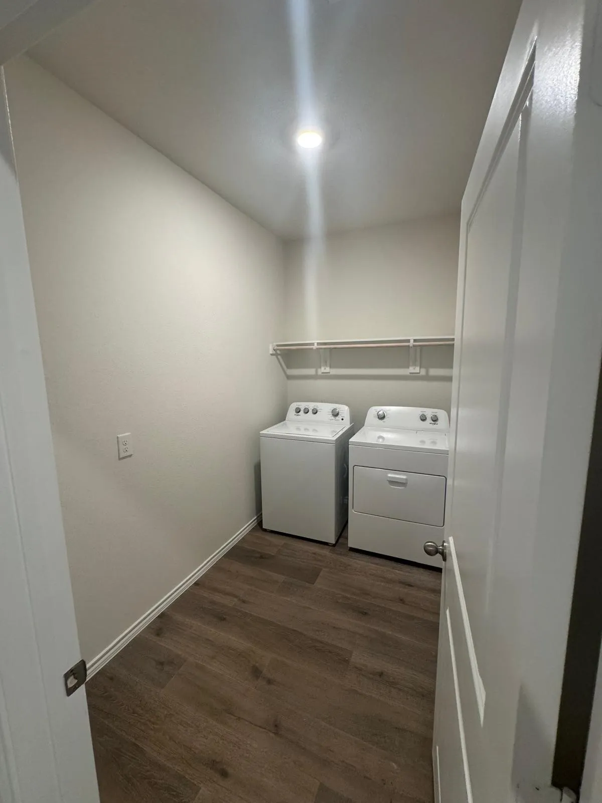Laundry area with dark wood finished floors and independent washer and dryer