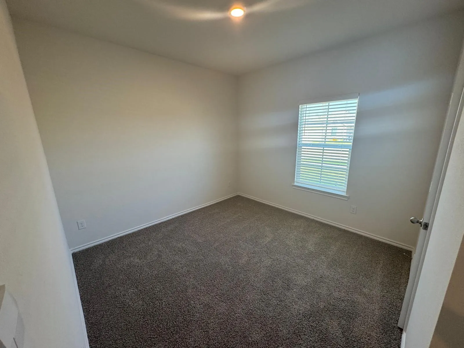 Empty room with dark carpet and baseboards
