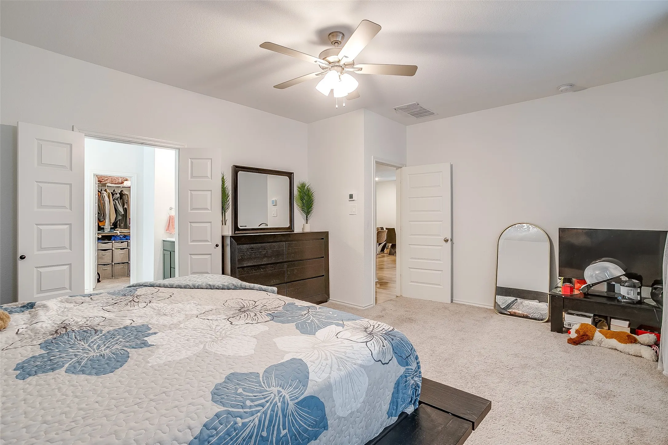 Bedroom featuring a ceiling fan, light-toned carpet flooring, white paneled doors, and an open entryway to a closet with built-in shelving