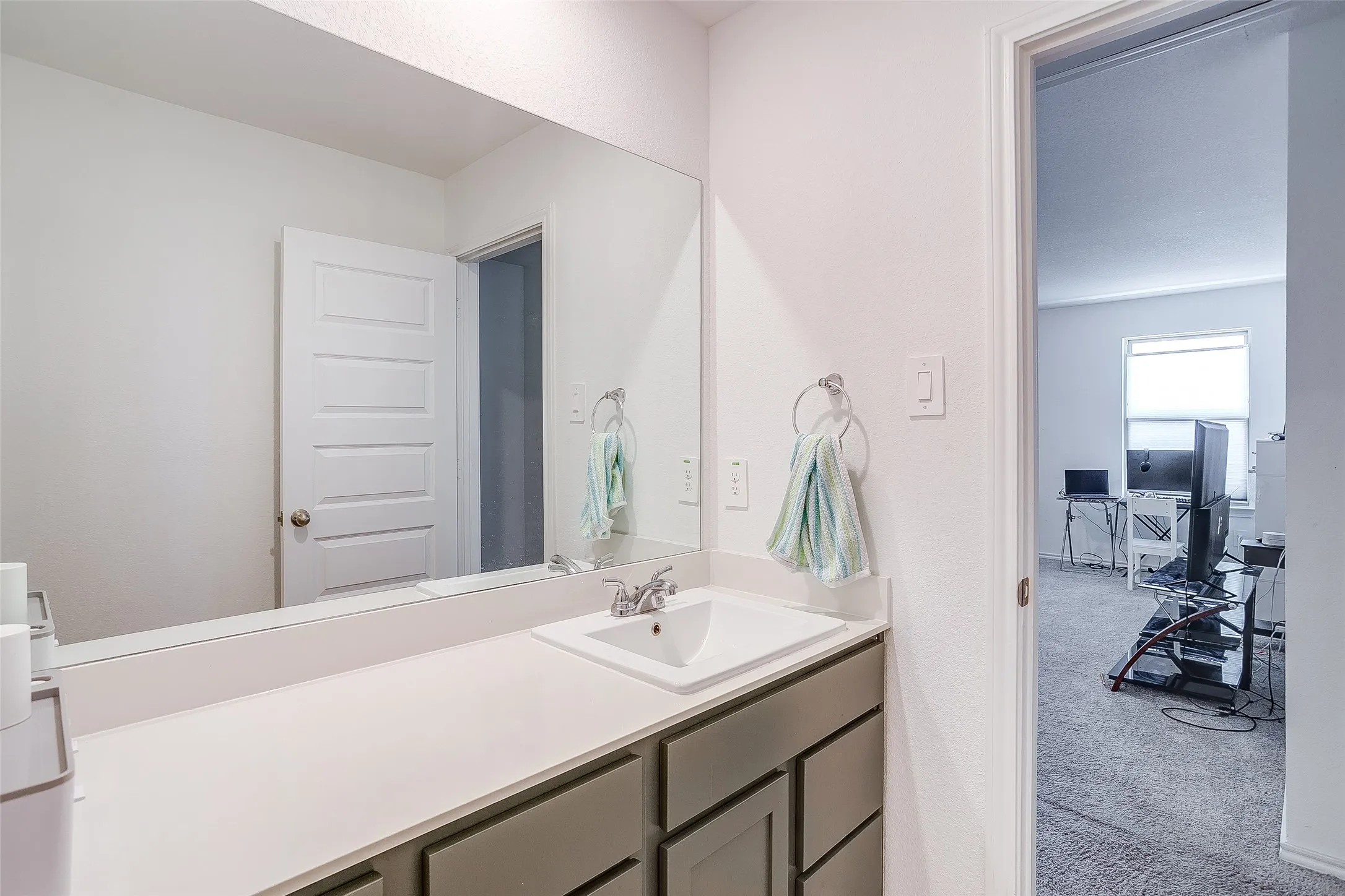Single vanity with a rectangular undermount sink, chrome faucet, and expansive wall-mounted mirror