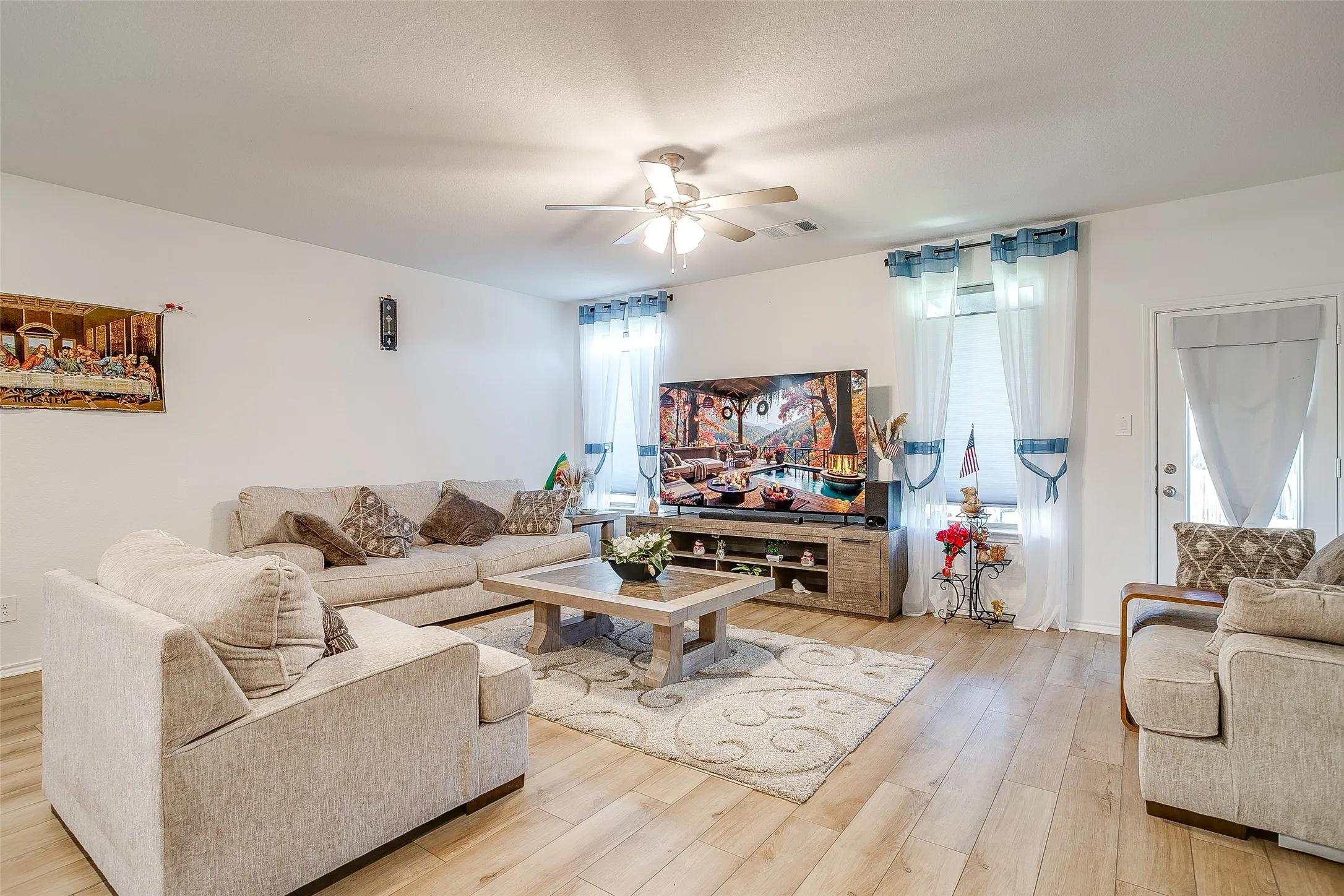 Recessed lighting, ceiling fan, wood-finish flooring, white walls, and a door with an exterior handle