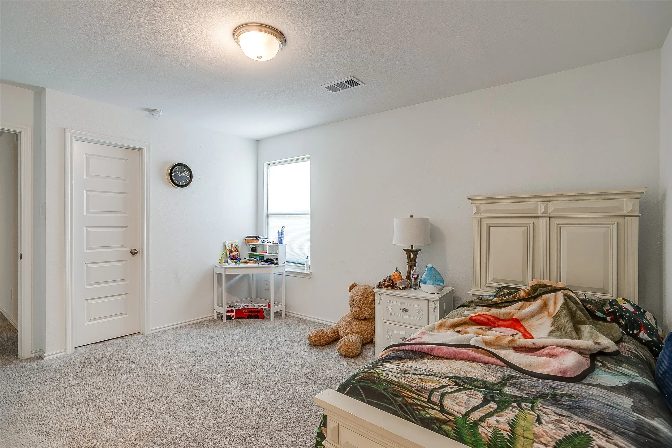 Neutral-toned wall-to-wall carpeting, white five-panel interior door, single window with blinds, and flush-mount ceiling light fixture