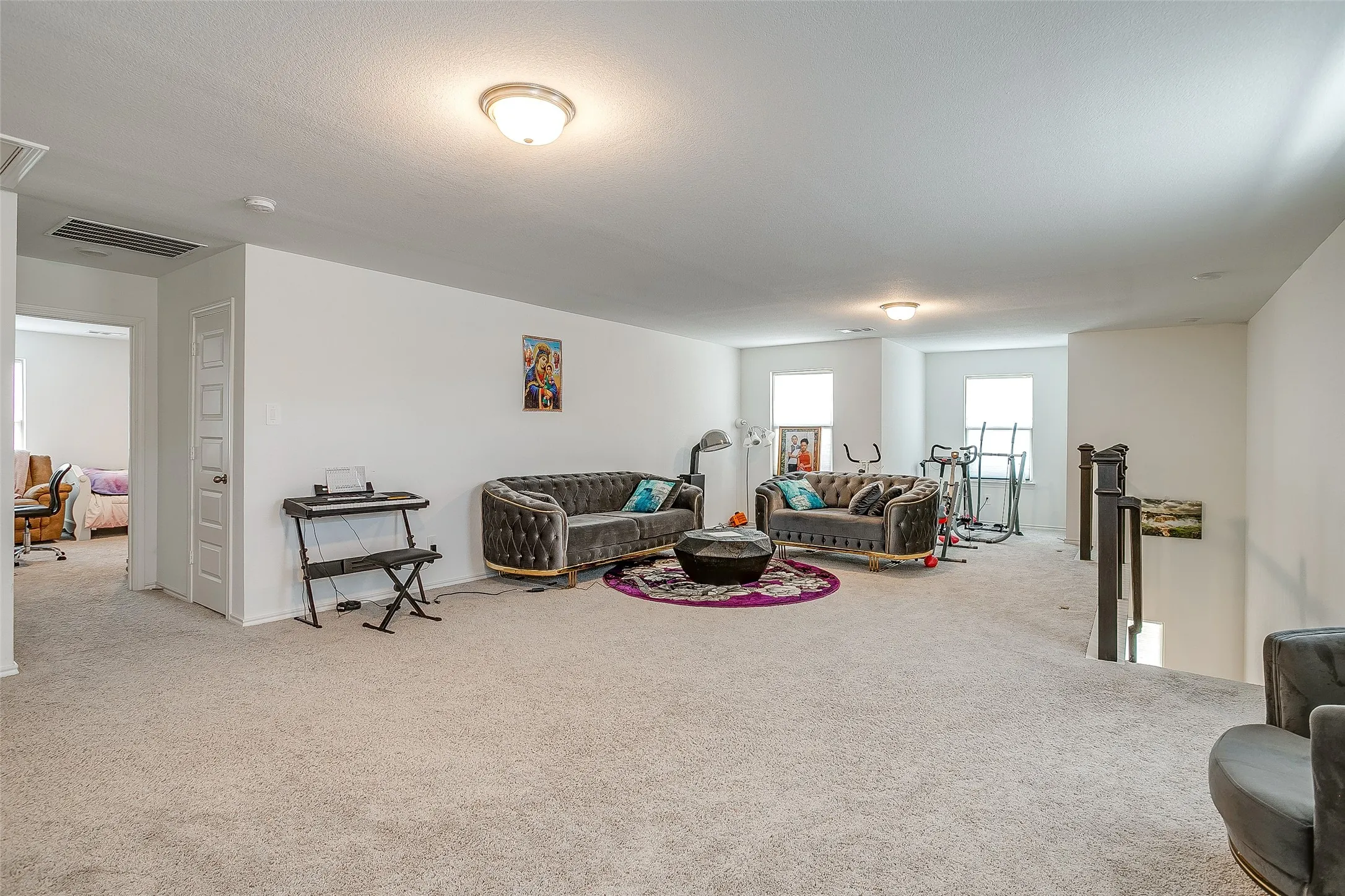 Expansive carpeted area with neutral walls, recessed lighting, and multiple windows providing natural light