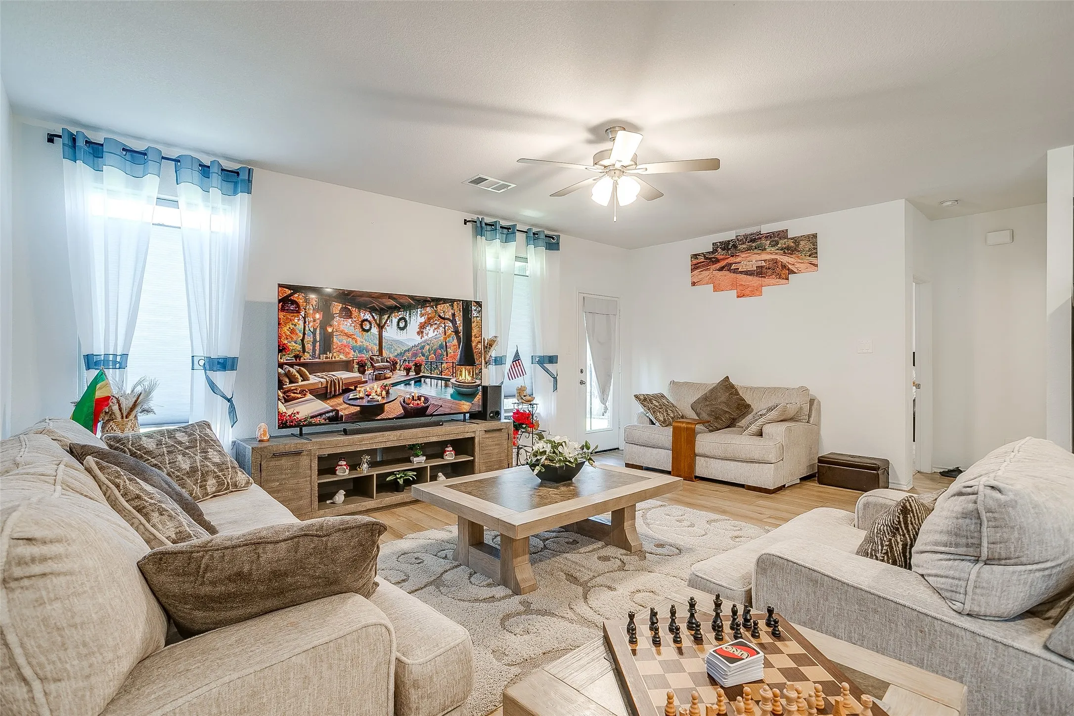 Spacious living area featuring light-toned flooring and a ceiling fan