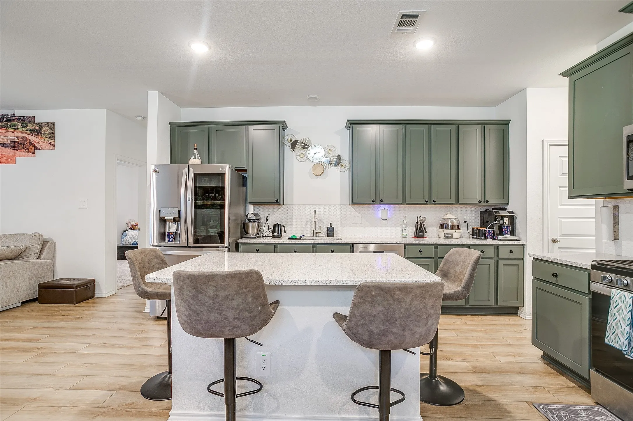 Kitchen featuring a central island with countertop seating, wood-finish flooring, recessed lighting, and green shaker-style cabinetry