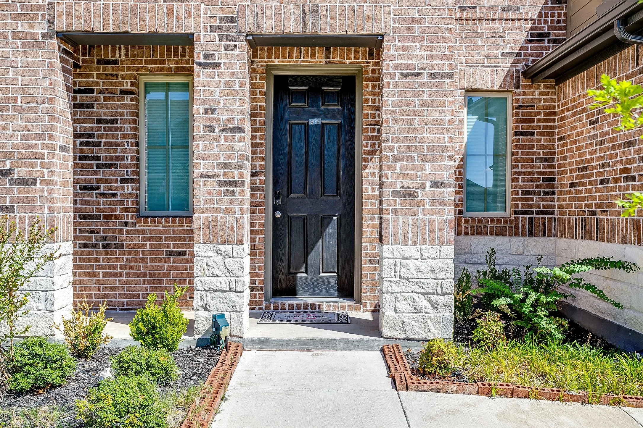 Brick exterior with stone accents, a dark wood-finish entry door, and slender windows