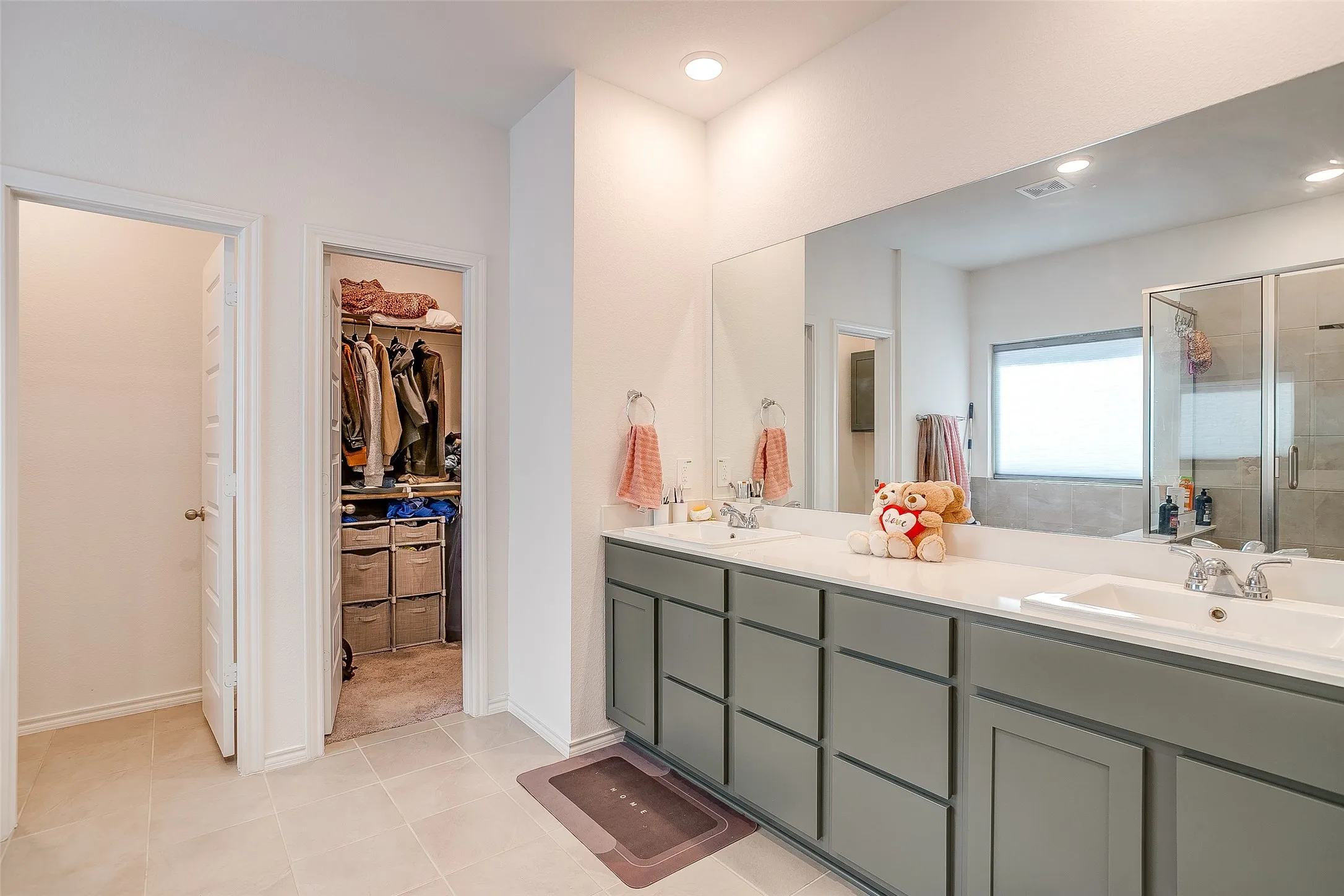Dual vanity with white countertops, integrated sinks, and gray cabinetry