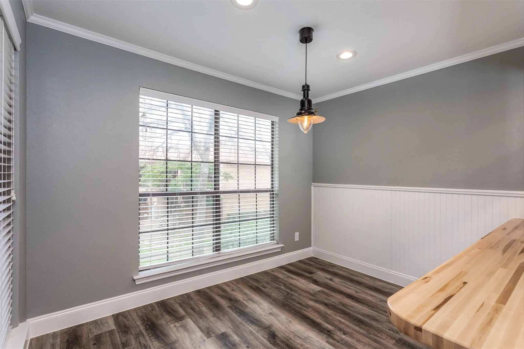 Dining room with lots of windows, oiled bronze lighting and access to butcher block breakfast bar to kitchen. Wood-like flooring.