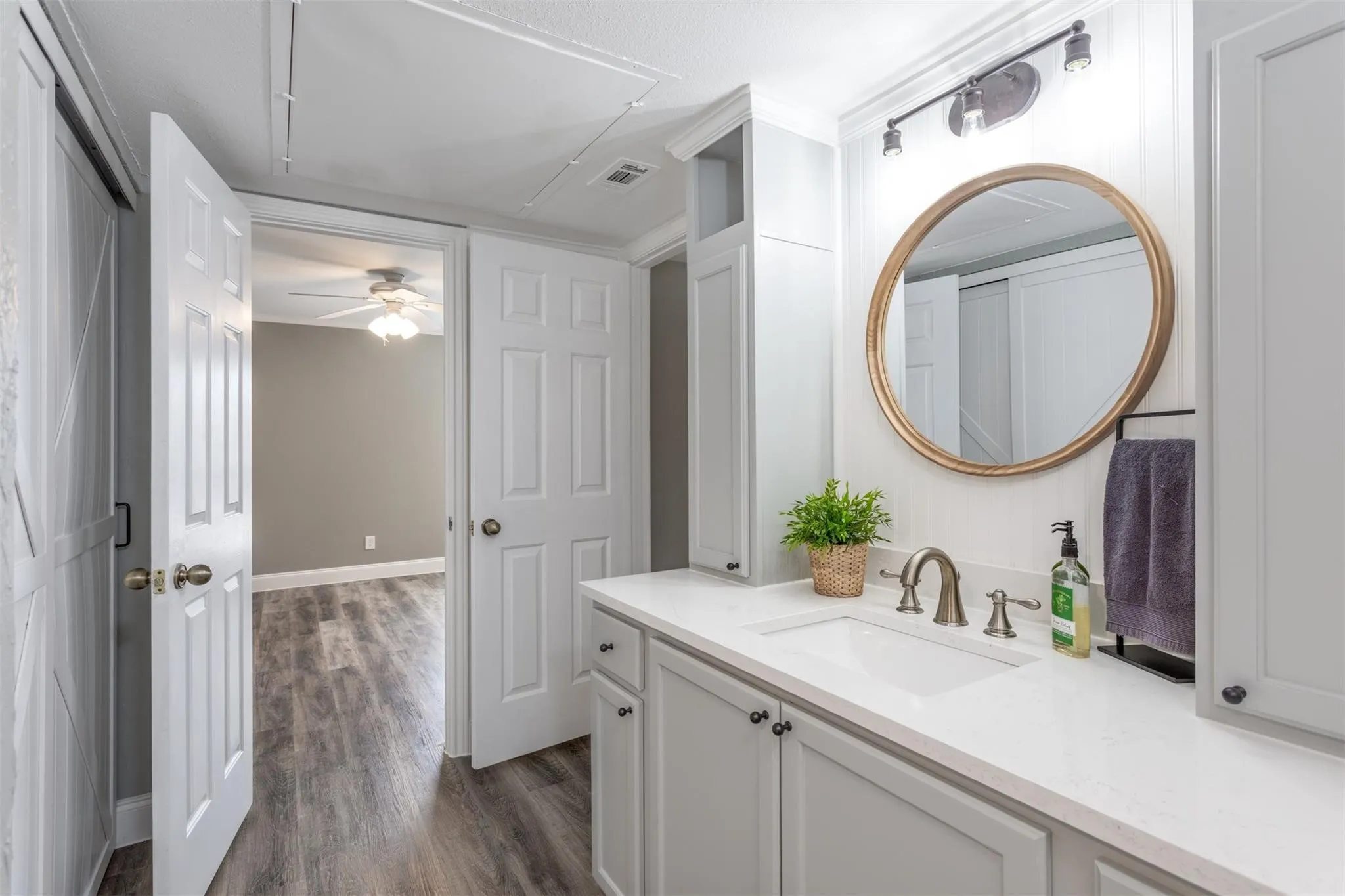 Beautiful updated bathroom with single sink, ample countertop space, storage and gold trimmed round mirror. Ensuite to bedroom and living area.