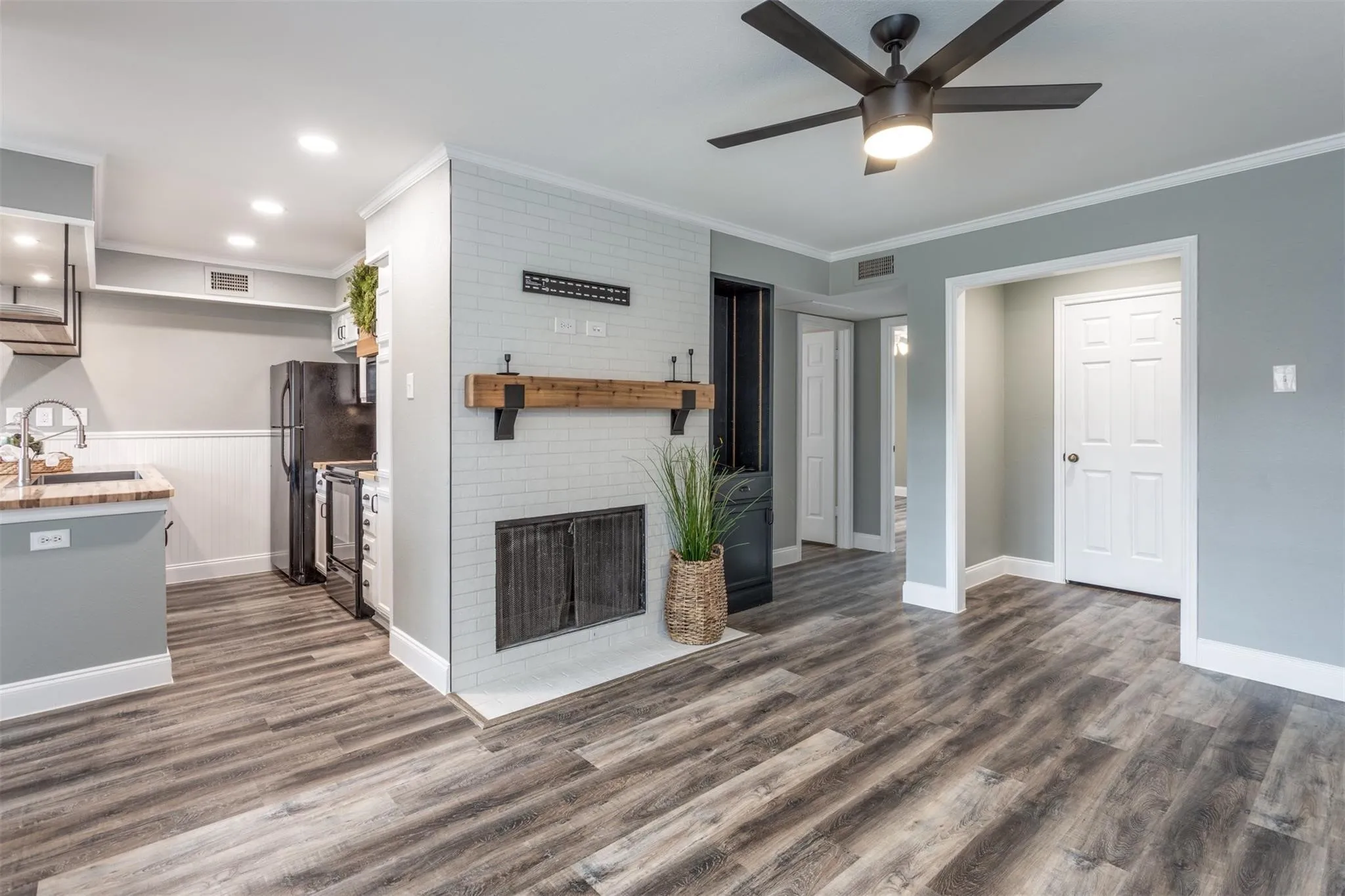 Stunning living space with wood fireplace, decorative mantle, ceiling fan and open concept to kitchen and dining areas.