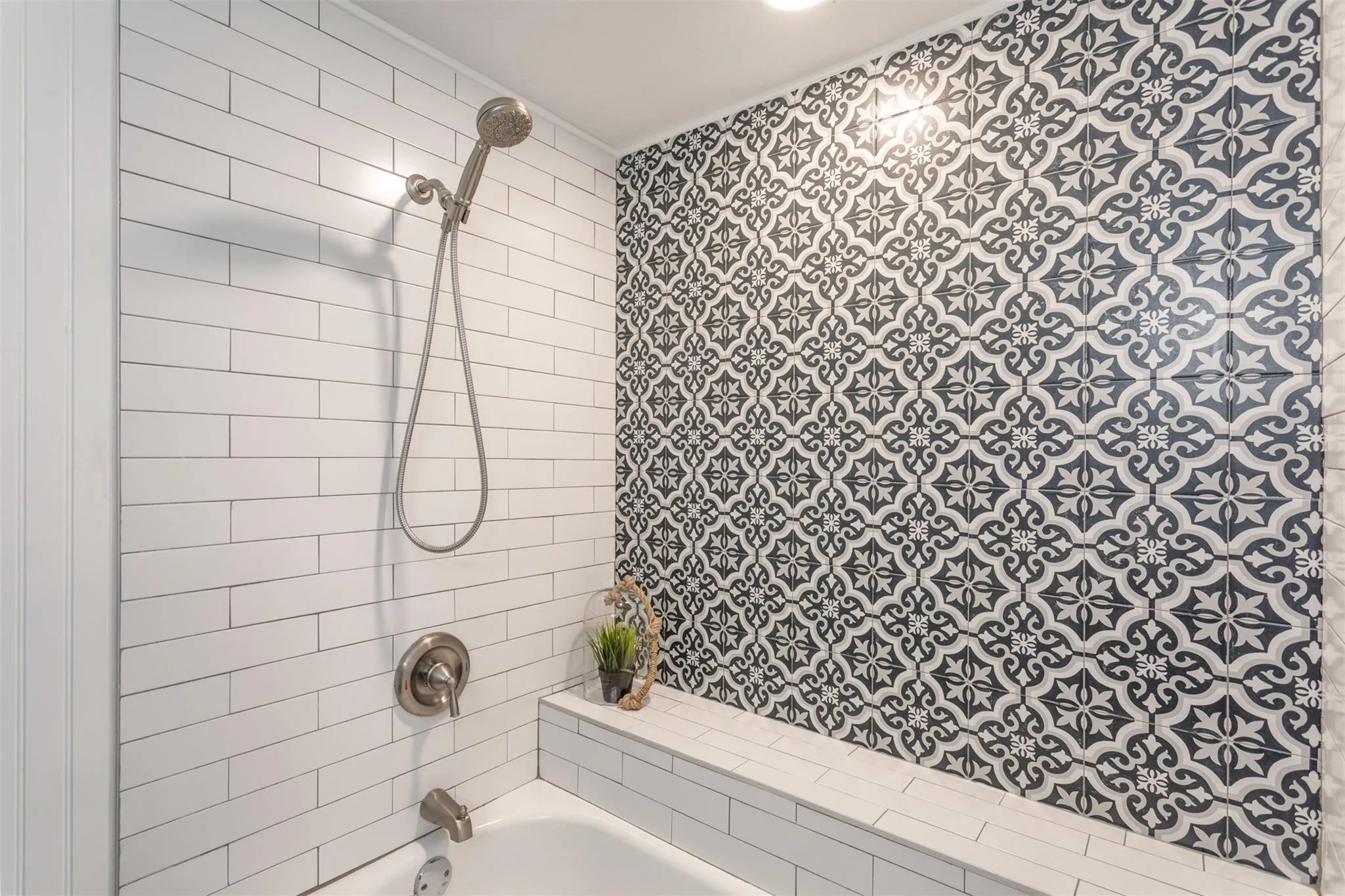 Tub/shower combo with blue accent textured tile wall and white subway tiles.