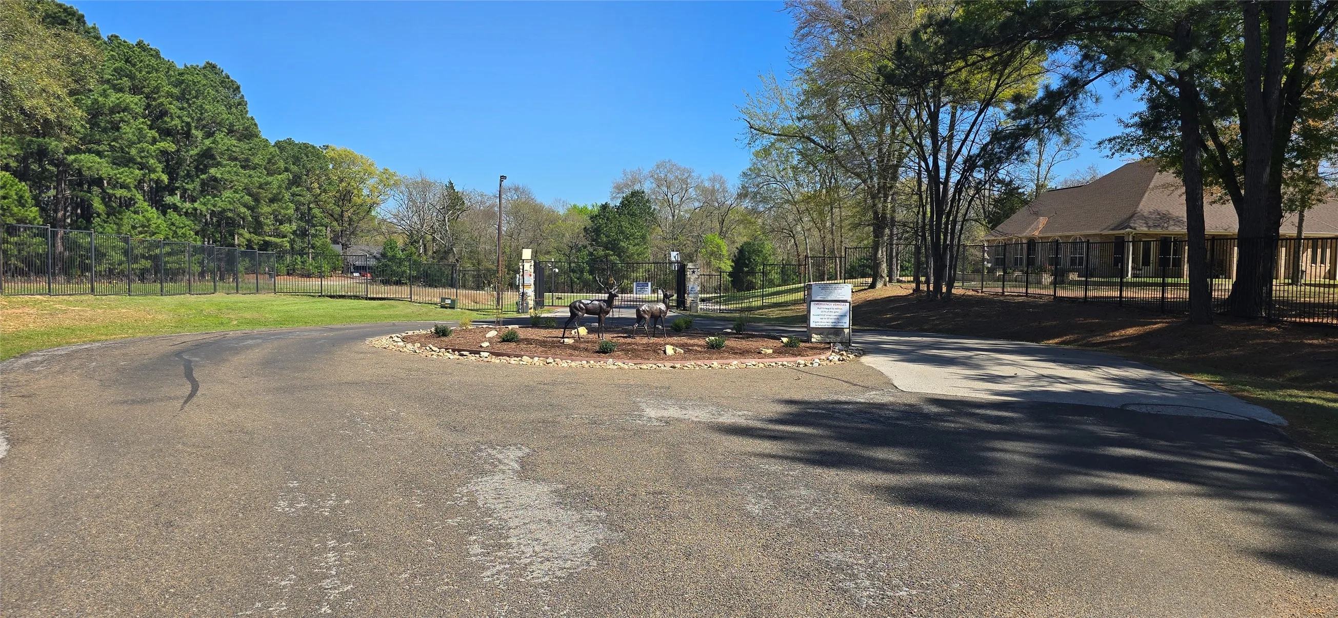 Gated entry with stone pillars, circular drive, and lush perimeter landscaping