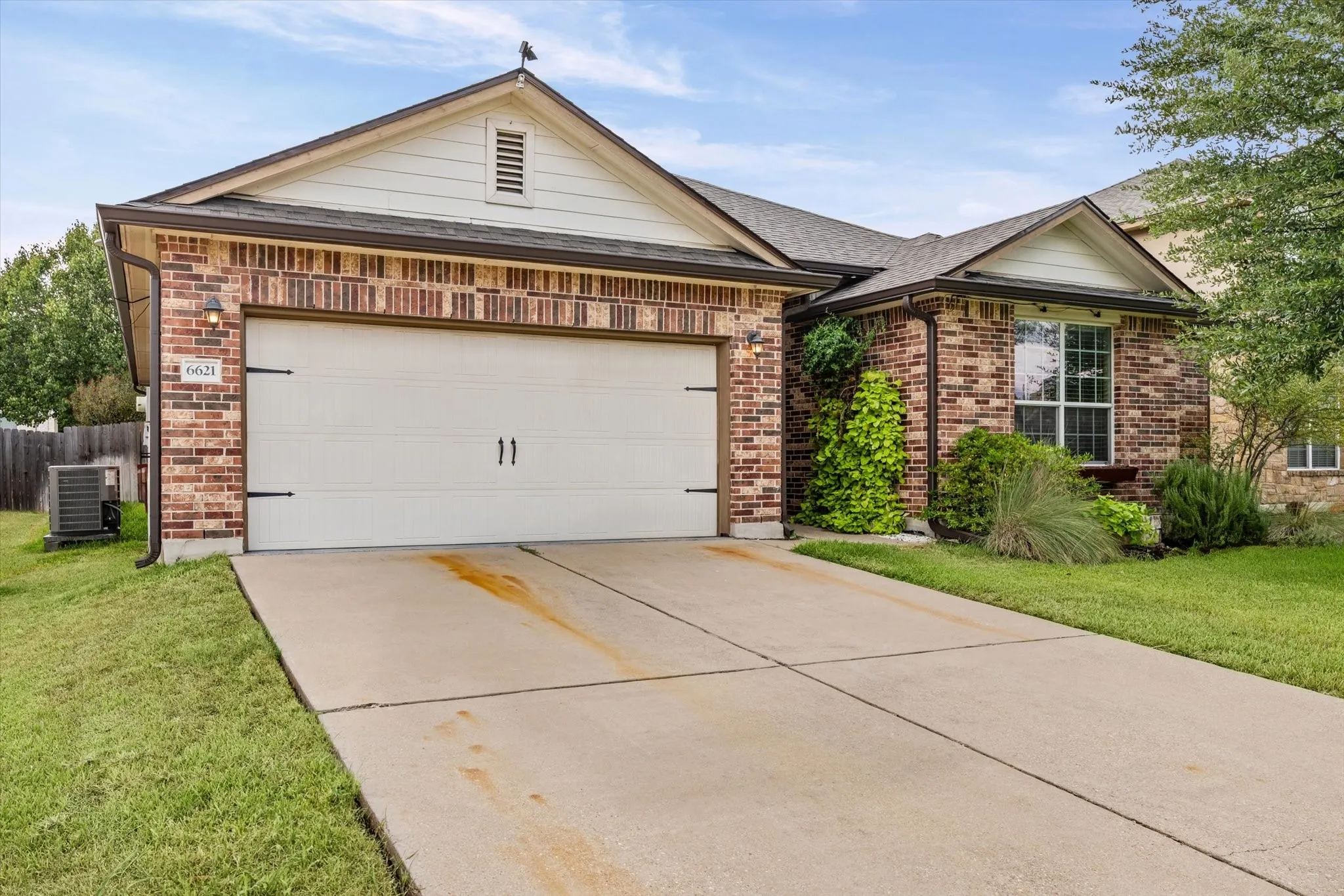 Brick exterior with a gabled roofline, a two-car garage, and landscaped front yard