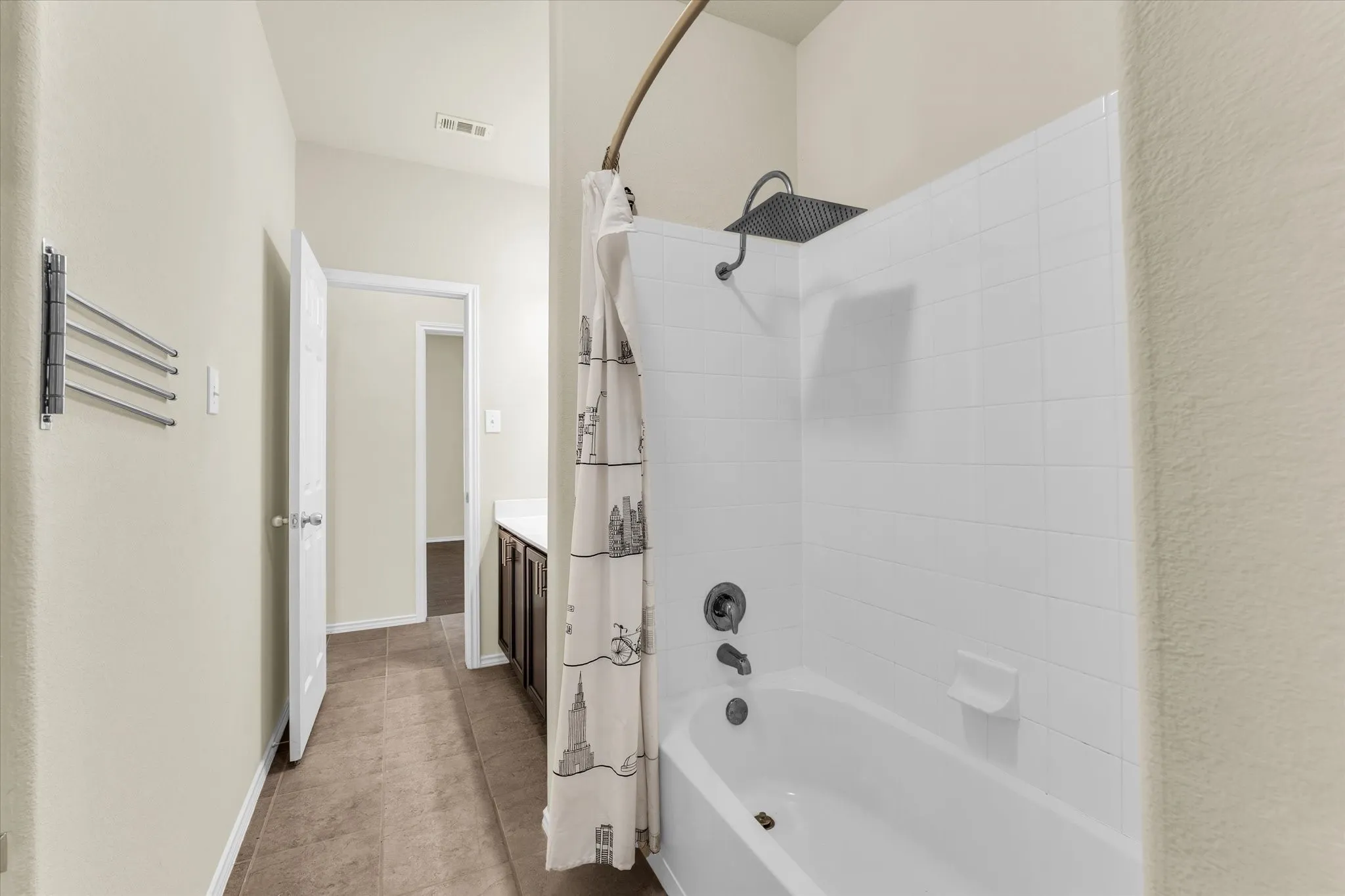 Bathtub with white tile surround, rainfall showerhead, and dark bronze fixtures