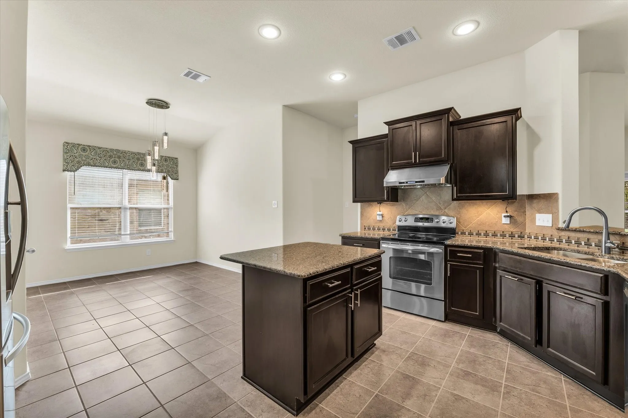 Kitchen featuring dark wood cabinetry, stainless steel appliances, a center island, and tile flooring