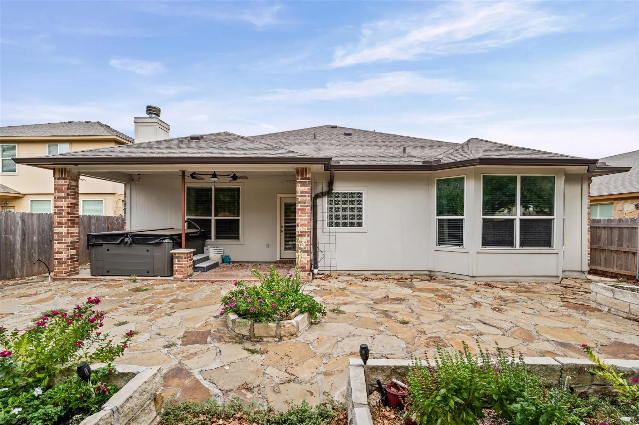 Expansive flagstone patio with a covered outdoor living area featuring brick columns