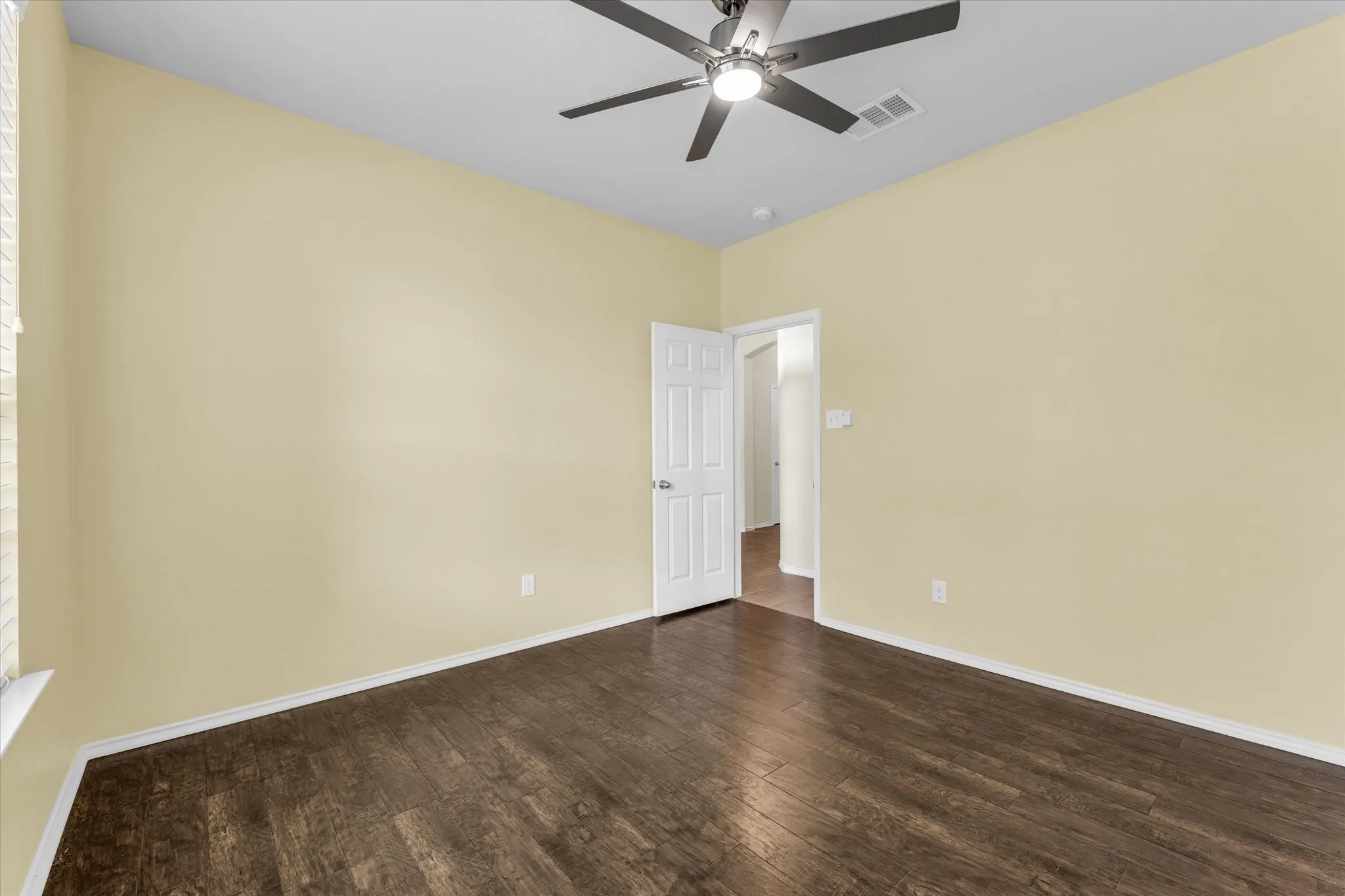 Wood-finish flooring, ceiling fan with integrated lighting, and a white paneled door
