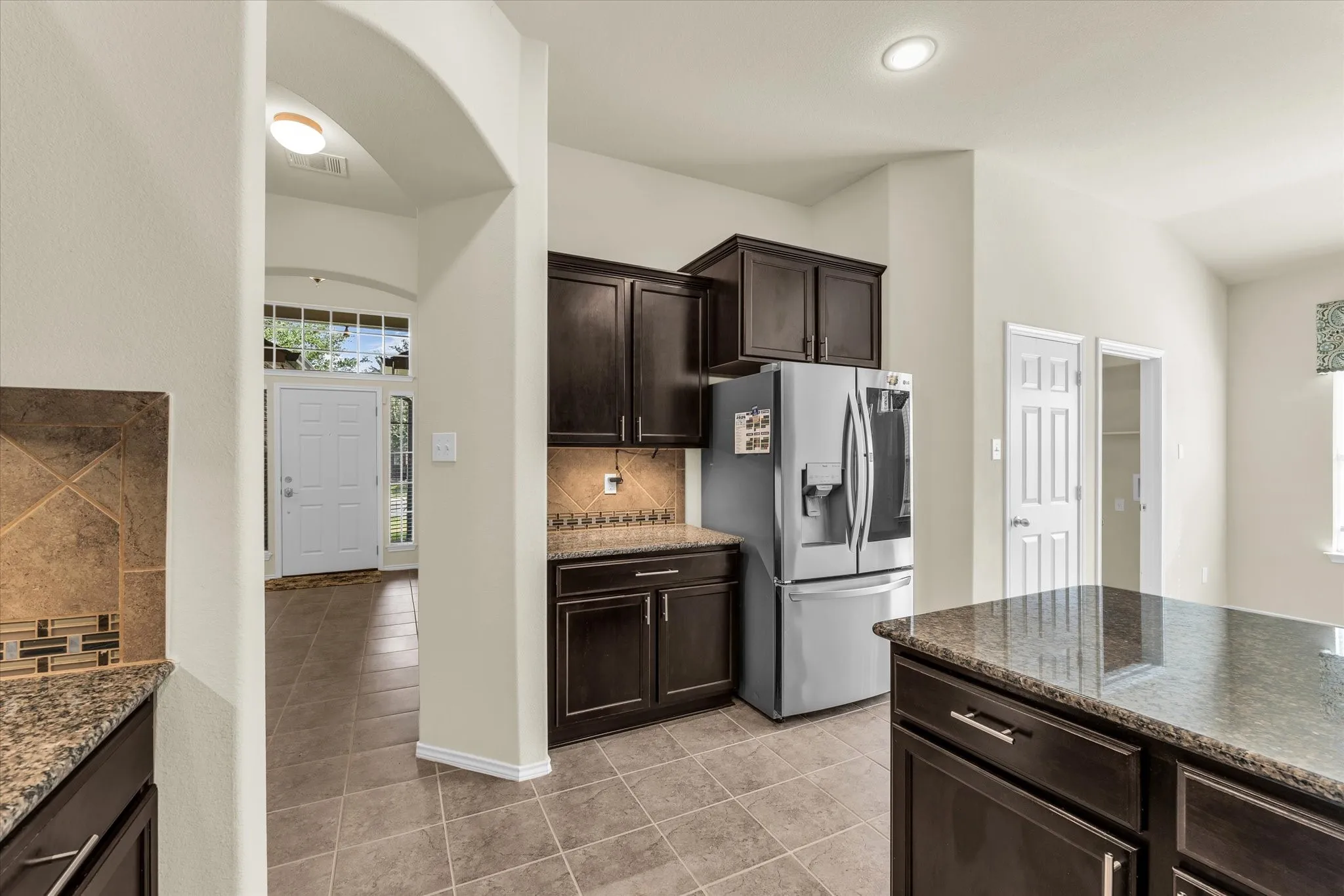 Kitchen featuring dark wood-finish cabinetry, granite-style countertops, and a tiled backsplash