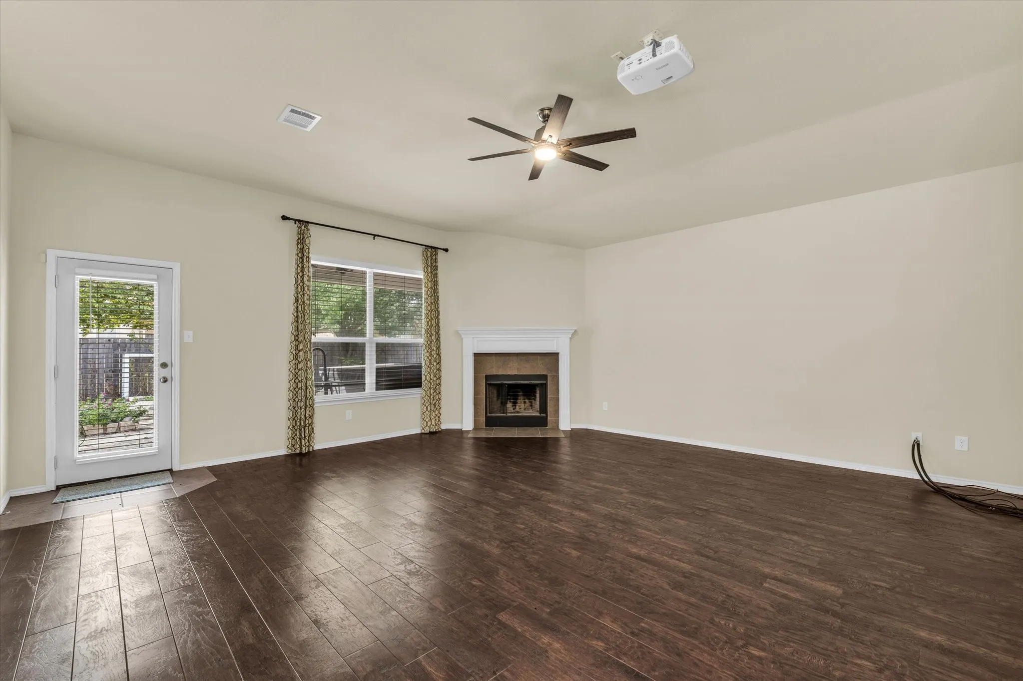 Wood-finish flooring, fireplace with a white mantel, ceiling fan, and a glass-paned exterior door