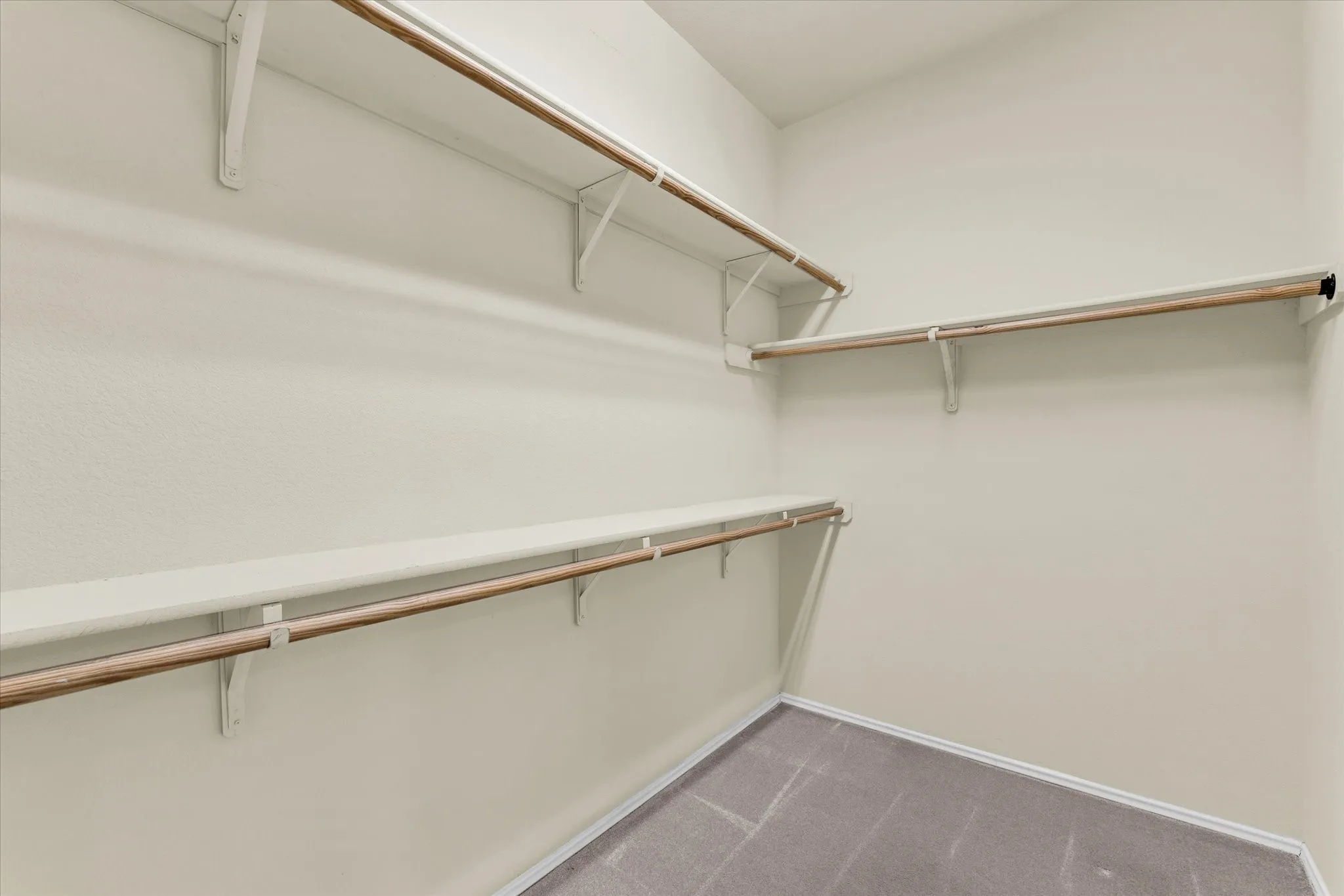 Walk-in closet with multiple shelving units and clothing rods