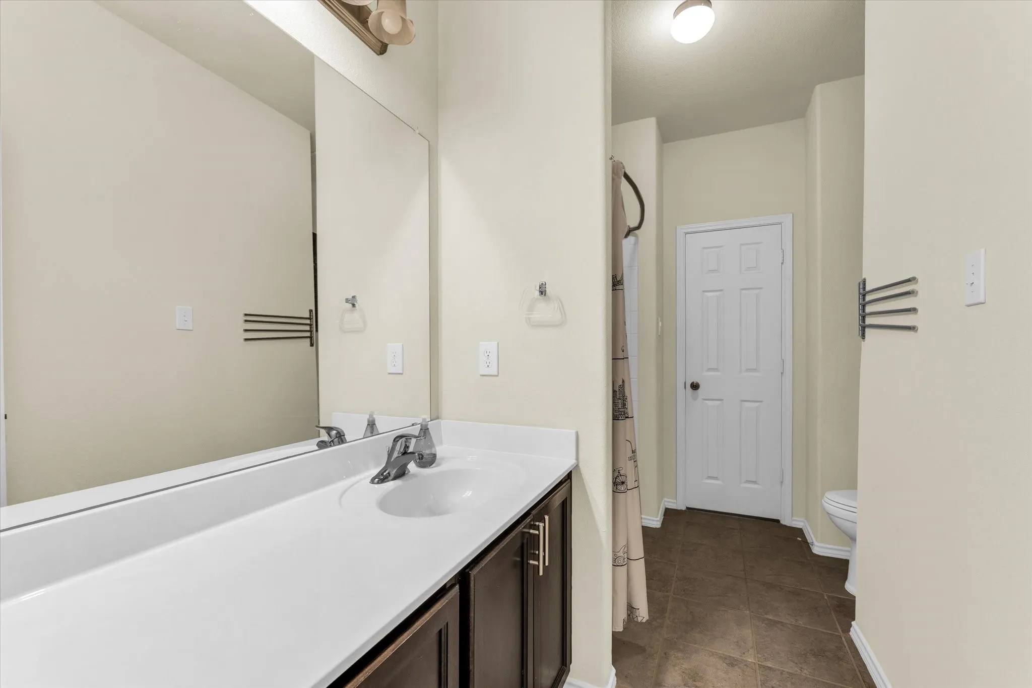 Vanity with integrated sink, chrome faucet, and brown wood-finish cabinetry