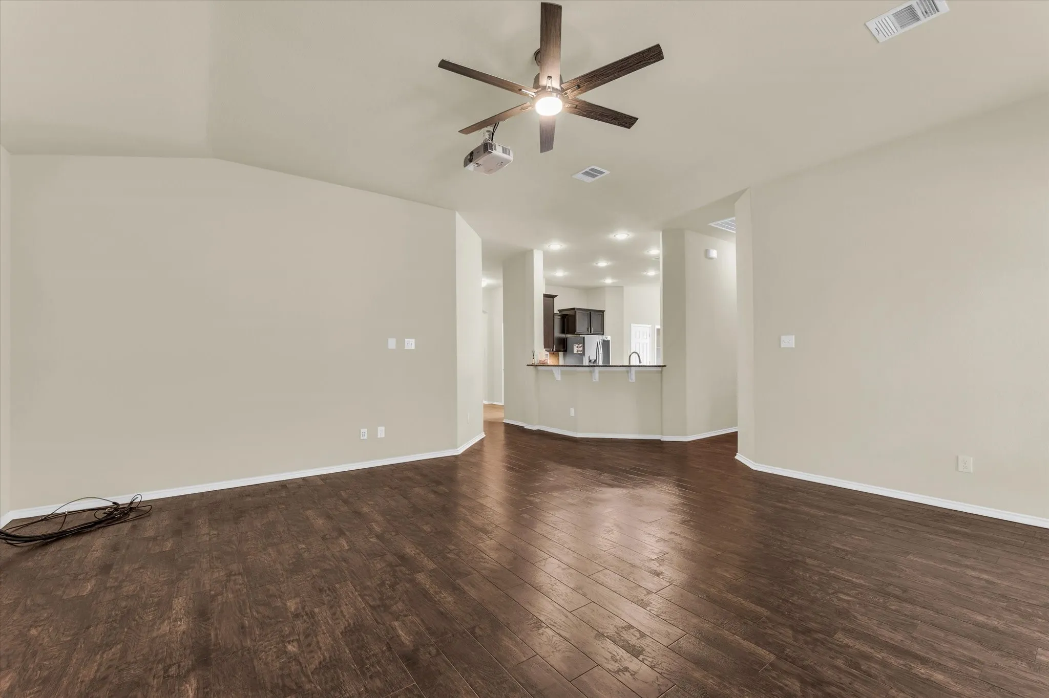Vaulted ceiling with a ceiling fan, wood-finish flooring, and recessed lighting in the kitchen area