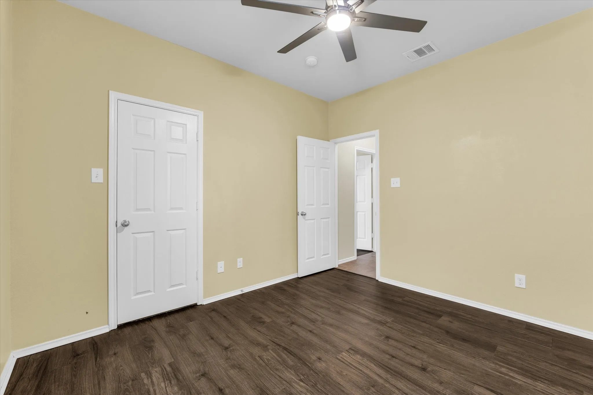 High ceilings with a ceiling fan, wood-finish flooring, and light-colored walls