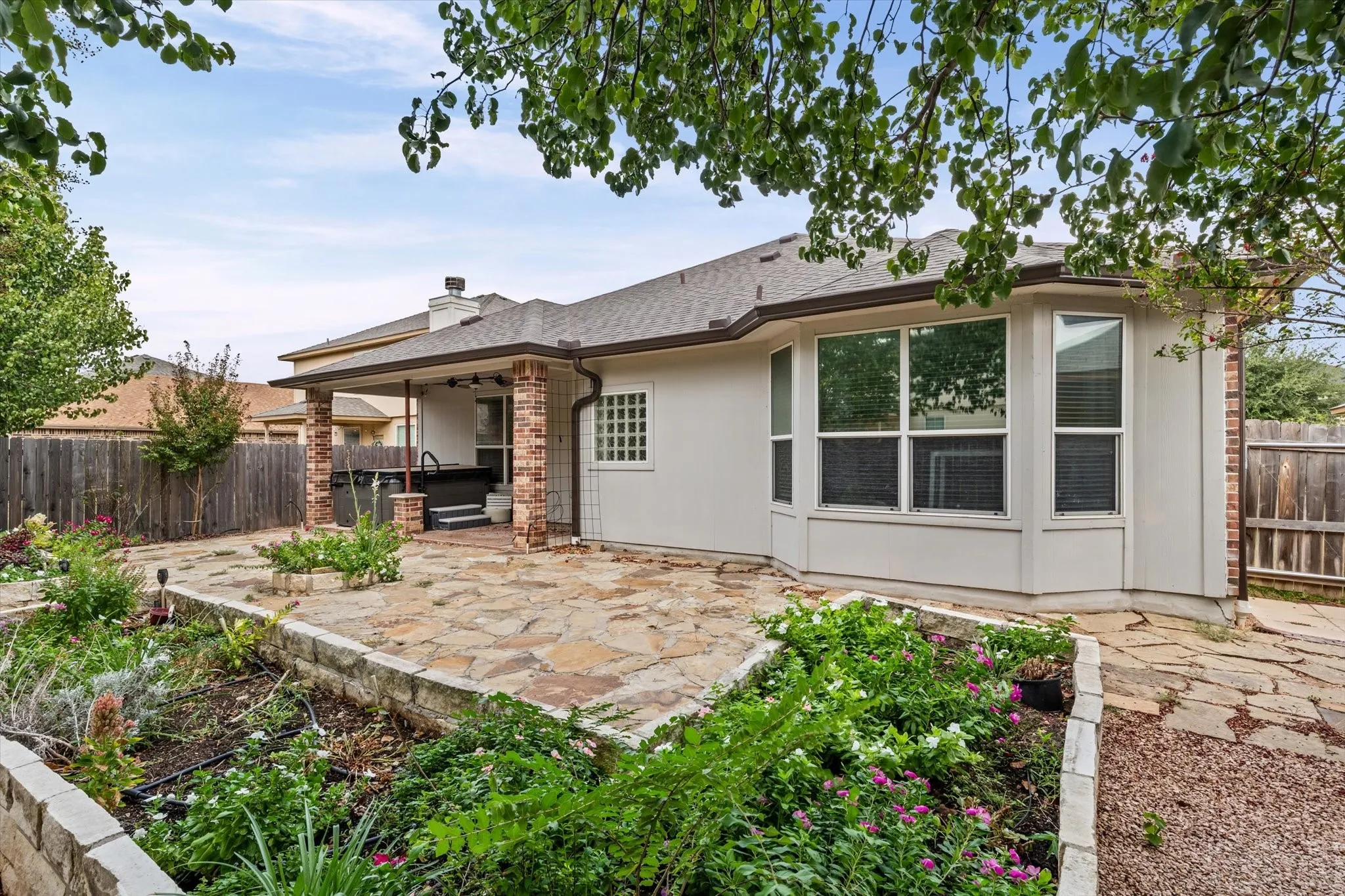 Expansive flagstone patio with a covered outdoor area, brick columns, and a built-in spa