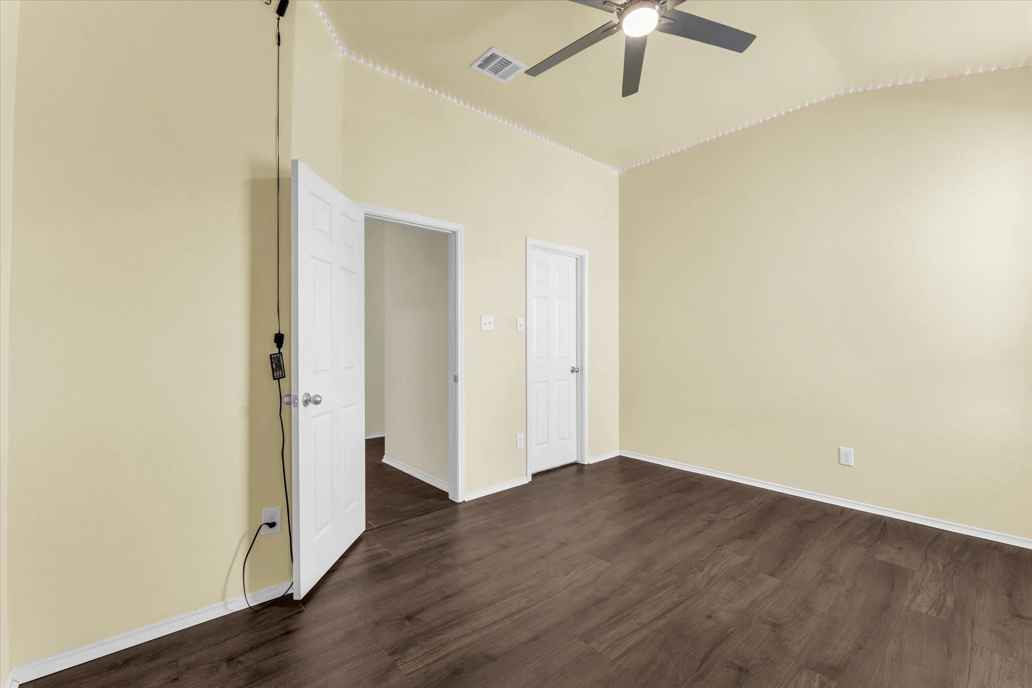 Vaulted ceiling, wood-finish flooring, ceiling fan with integrated lighting, crown molding, and paneled doors