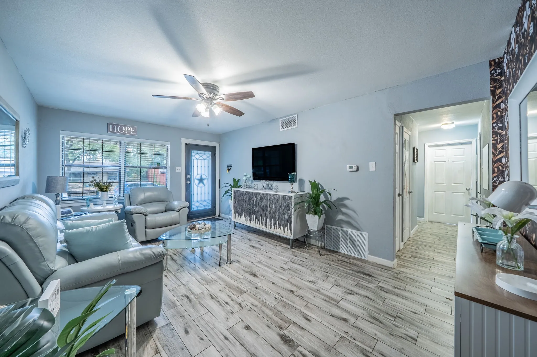 Wood-finish flooring, ceiling fan, multiple windows with blinds, recessed lighting, and a paneled interior door