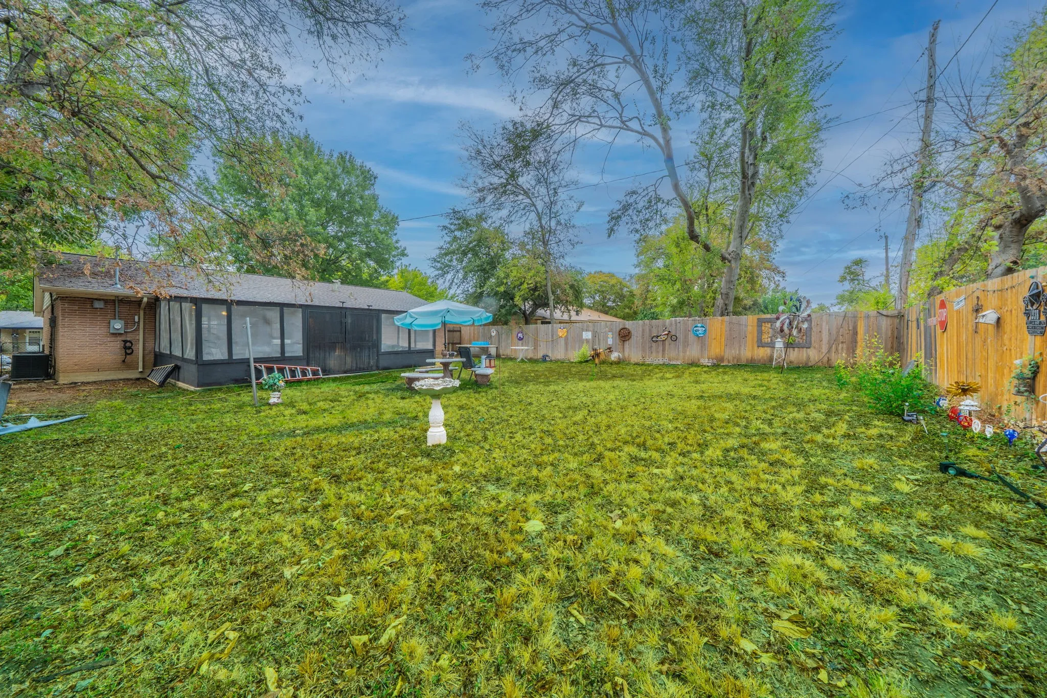 Expansive backyard featuring a manicured lawn, wood fencing, and a sunroom addition