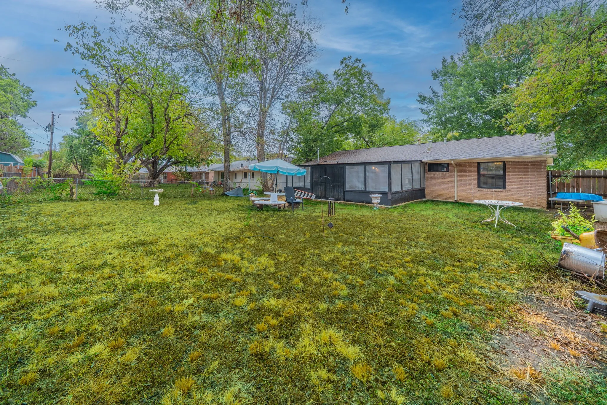 Expansive level lot with mature shade trees and lush lawn, anchored by a brick residence and modern black-clad addition