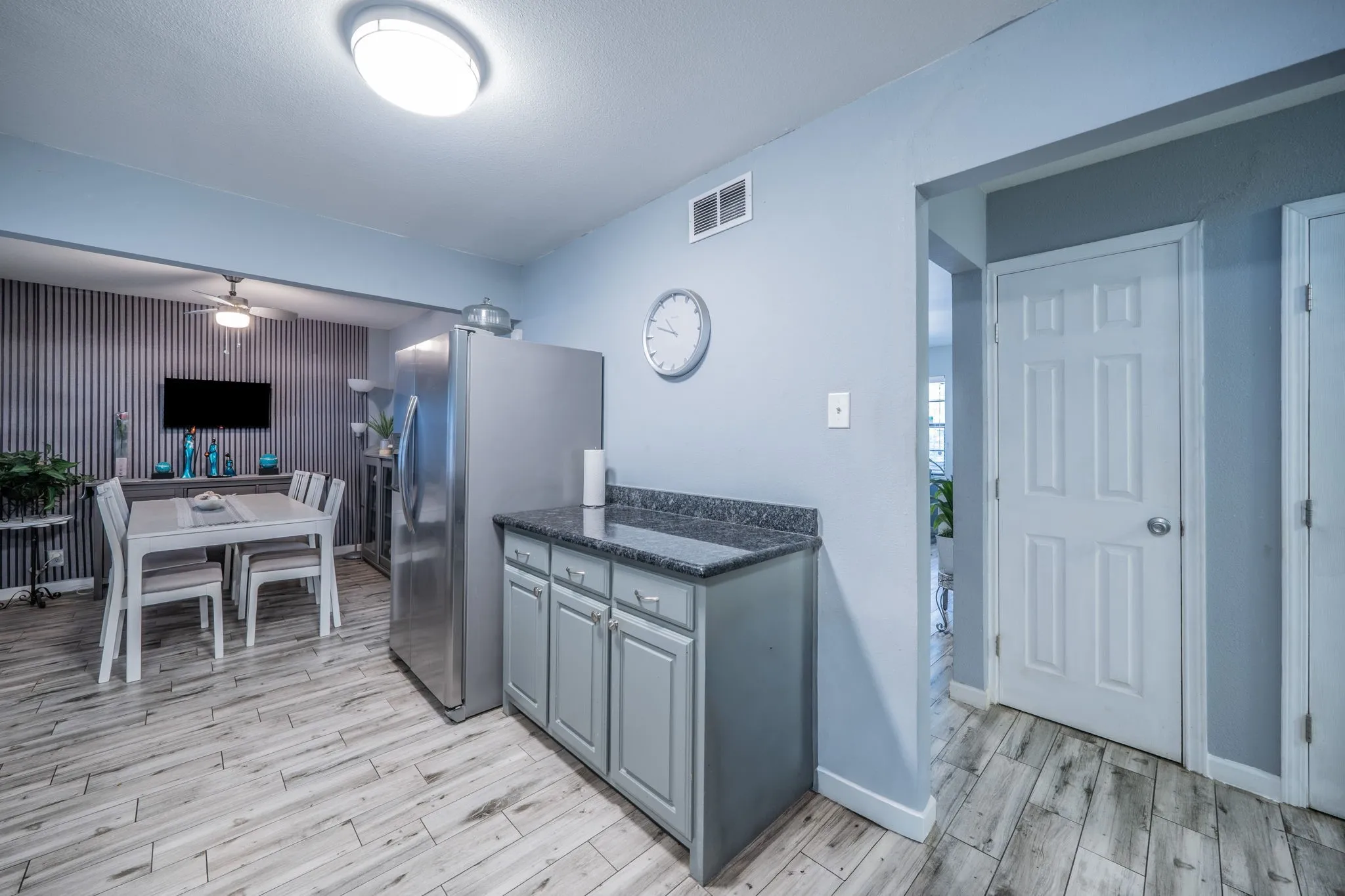 Wood-finish flooring, recessed lighting, built-in cabinetry with dark countertops, and a modern ceiling fan