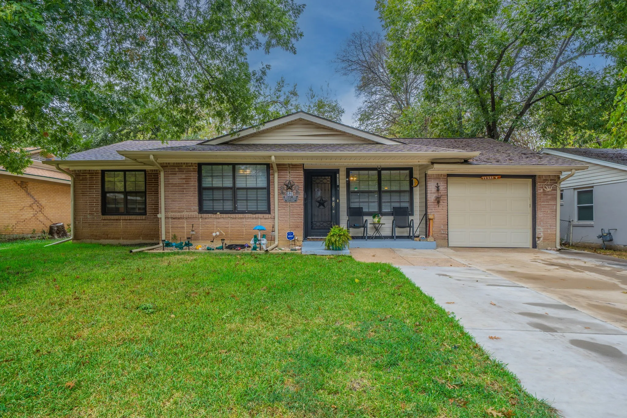 Charming brick ranch home featuring a welcoming front elevation with a covered entry portico, black-trimmed windows, and a two-car attached garage