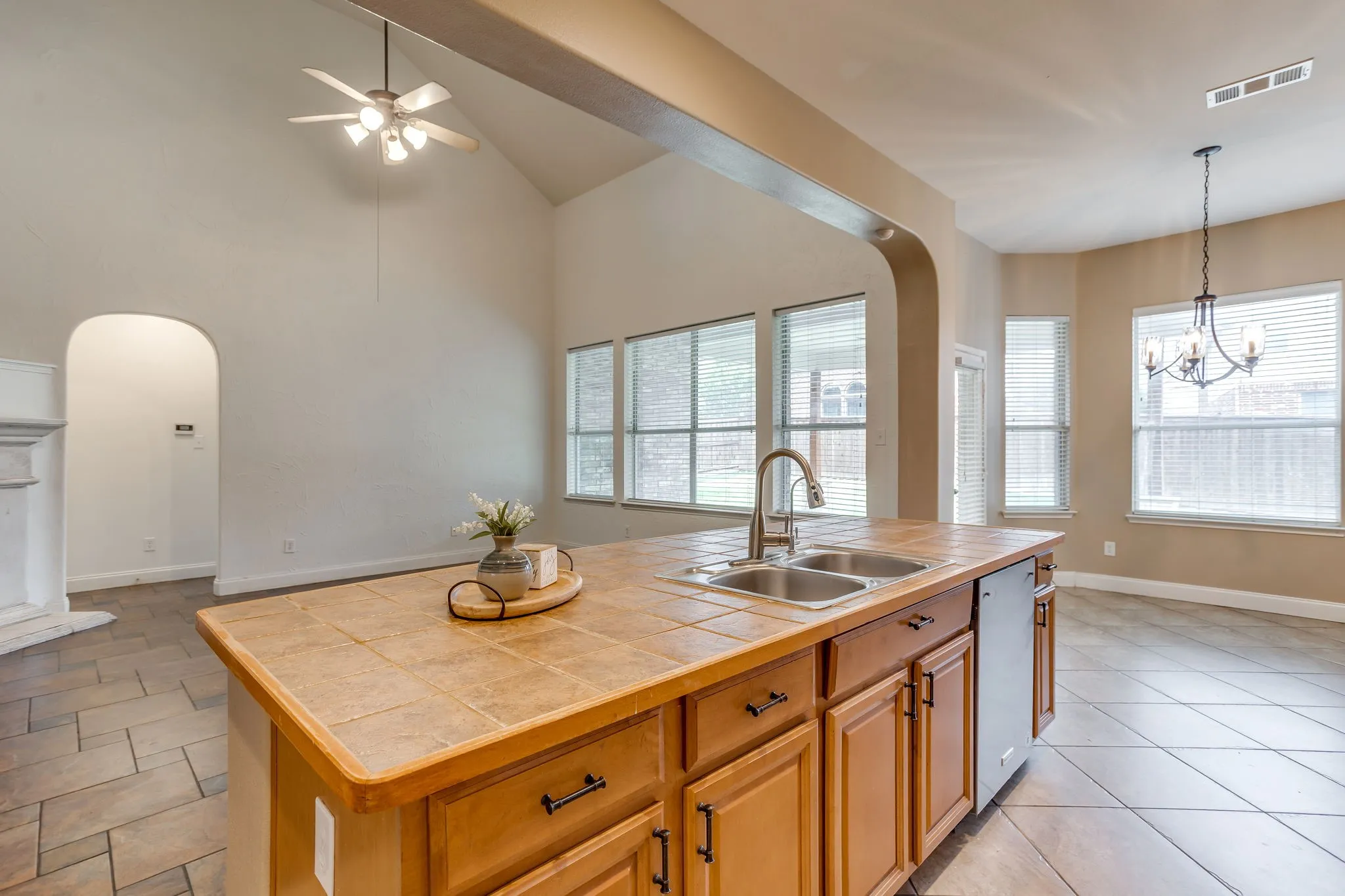 Kitchen island with a tile countertop, double basin sink, and wood cabinetry
