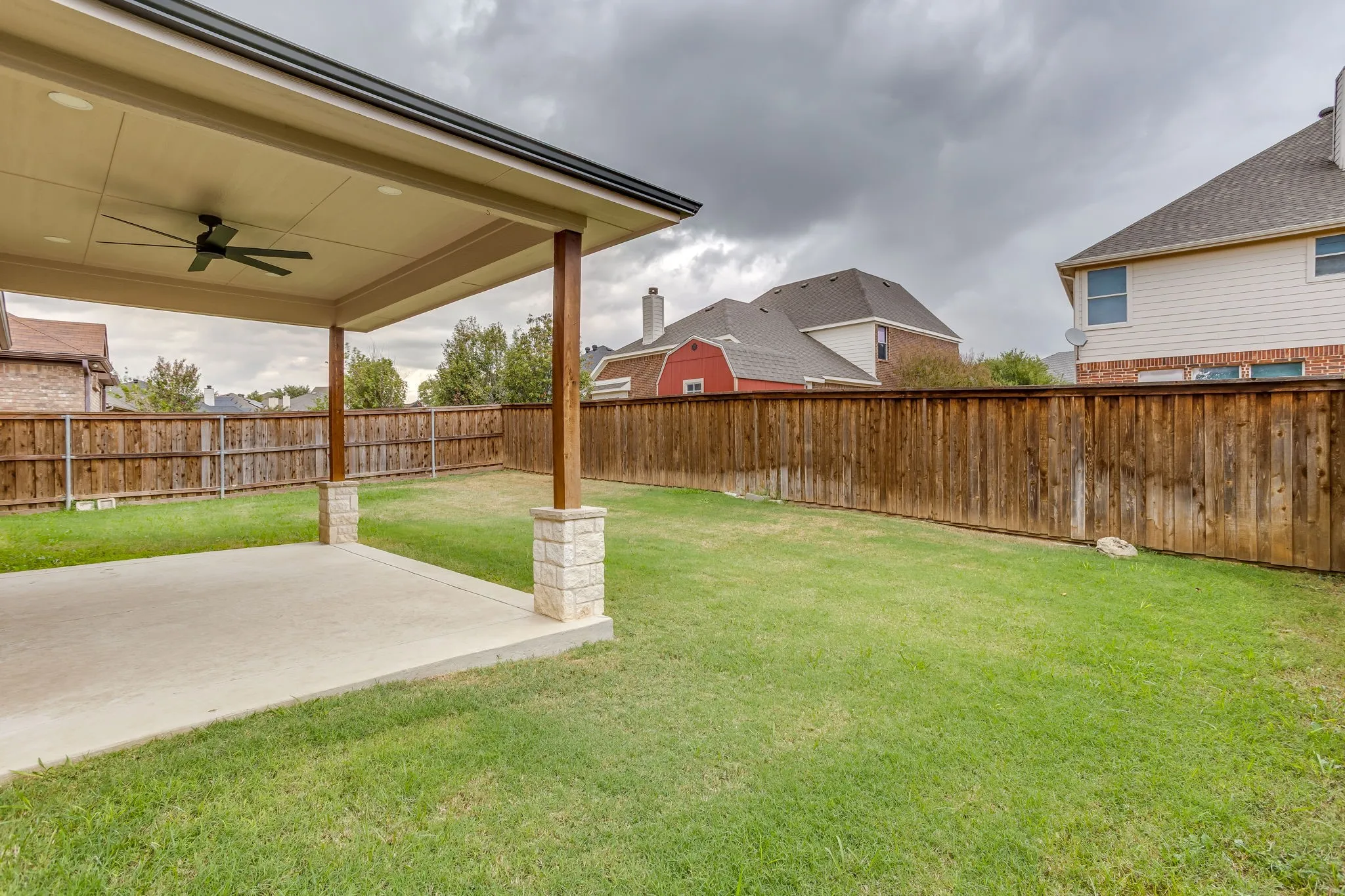 Covered patio featuring an outdoor ceiling fan, recessed lighting, and stone column bases
