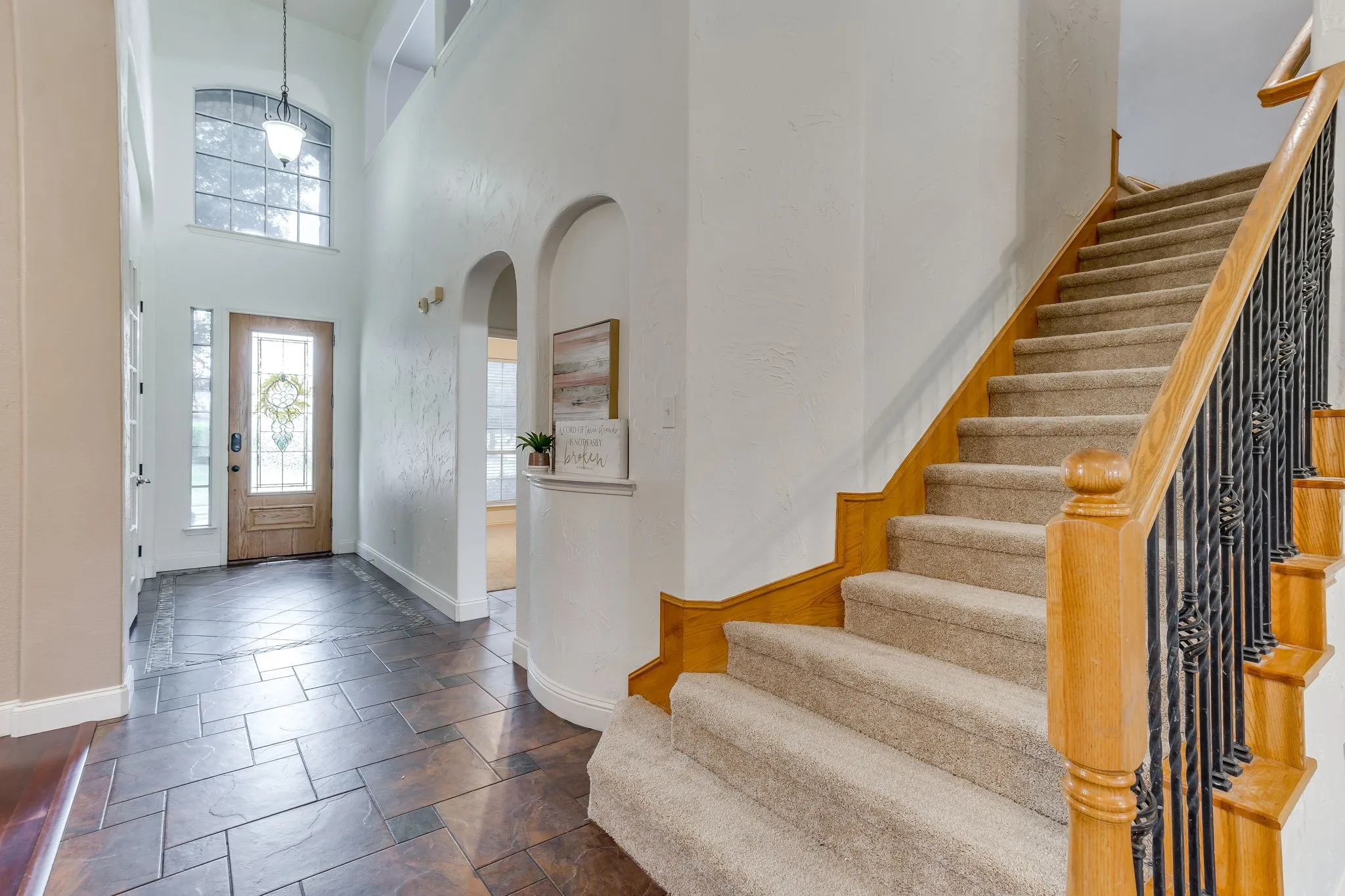 Two-story foyer with tile flooring and an arched entryway