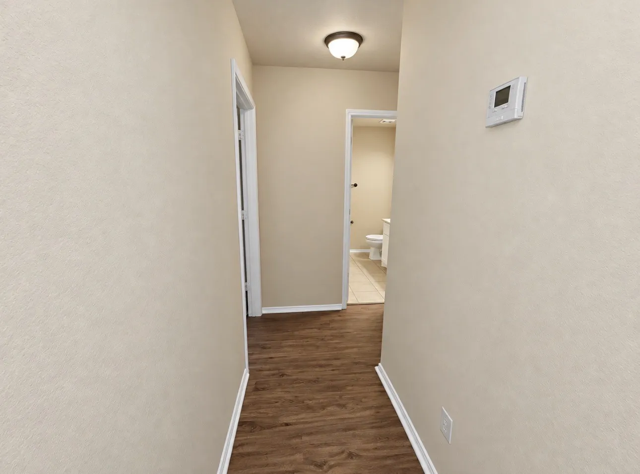 Wood-finish flooring throughout, complemented by a contemporary wall-mounted thermostat