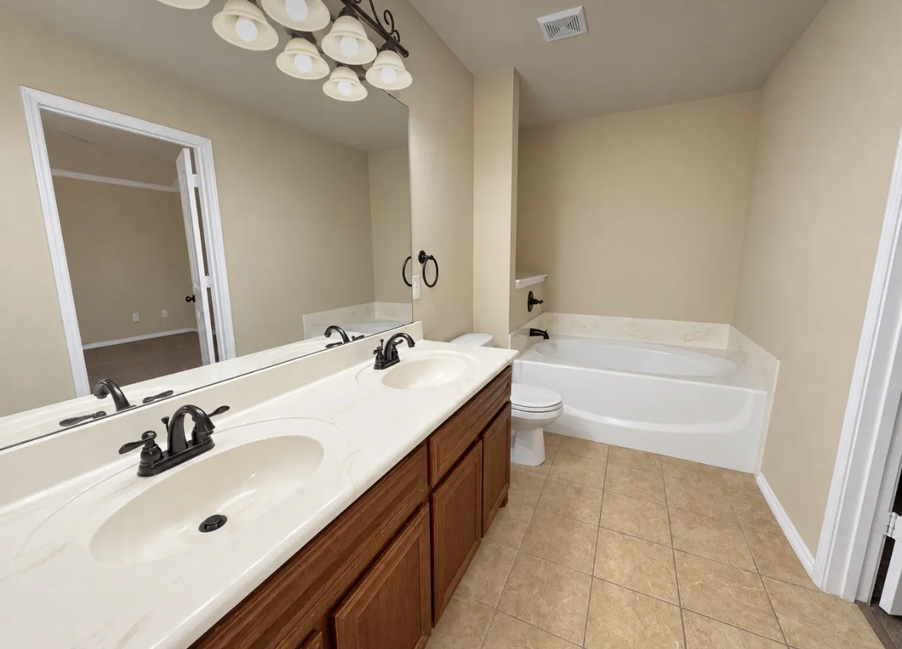Dual vanity with dark wood-finish cabinetry, integrated sinks, and bronze-finish fixtures
