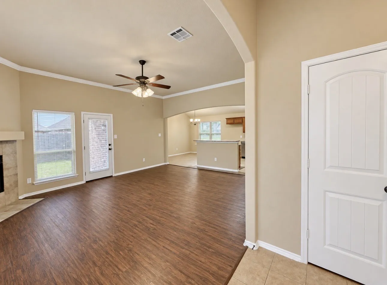 Spacious living area featuring wood-finish flooring, a ceiling fan, and crown molding